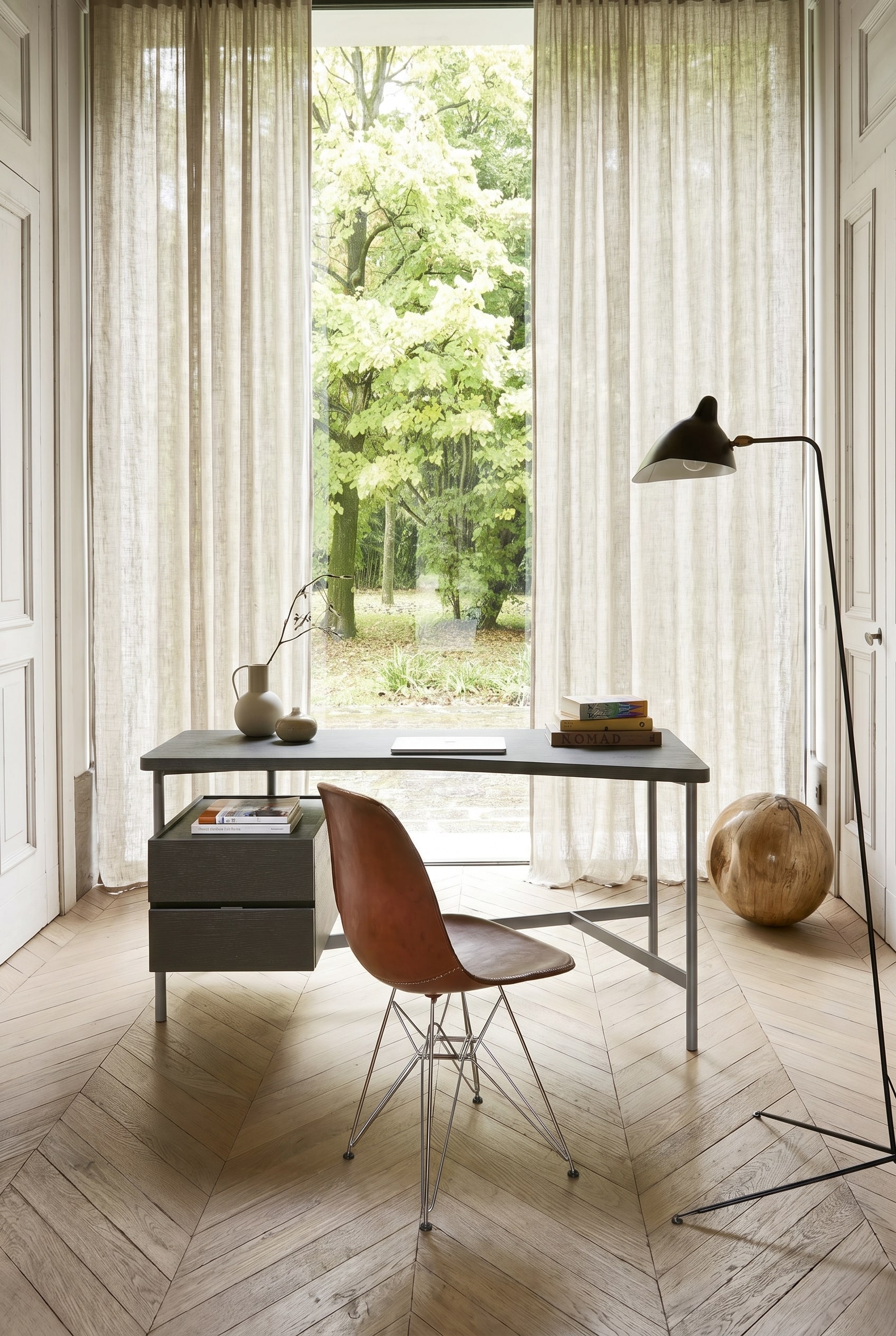 A very slim, minimalist desk with a metal frame in a bright guest room.
