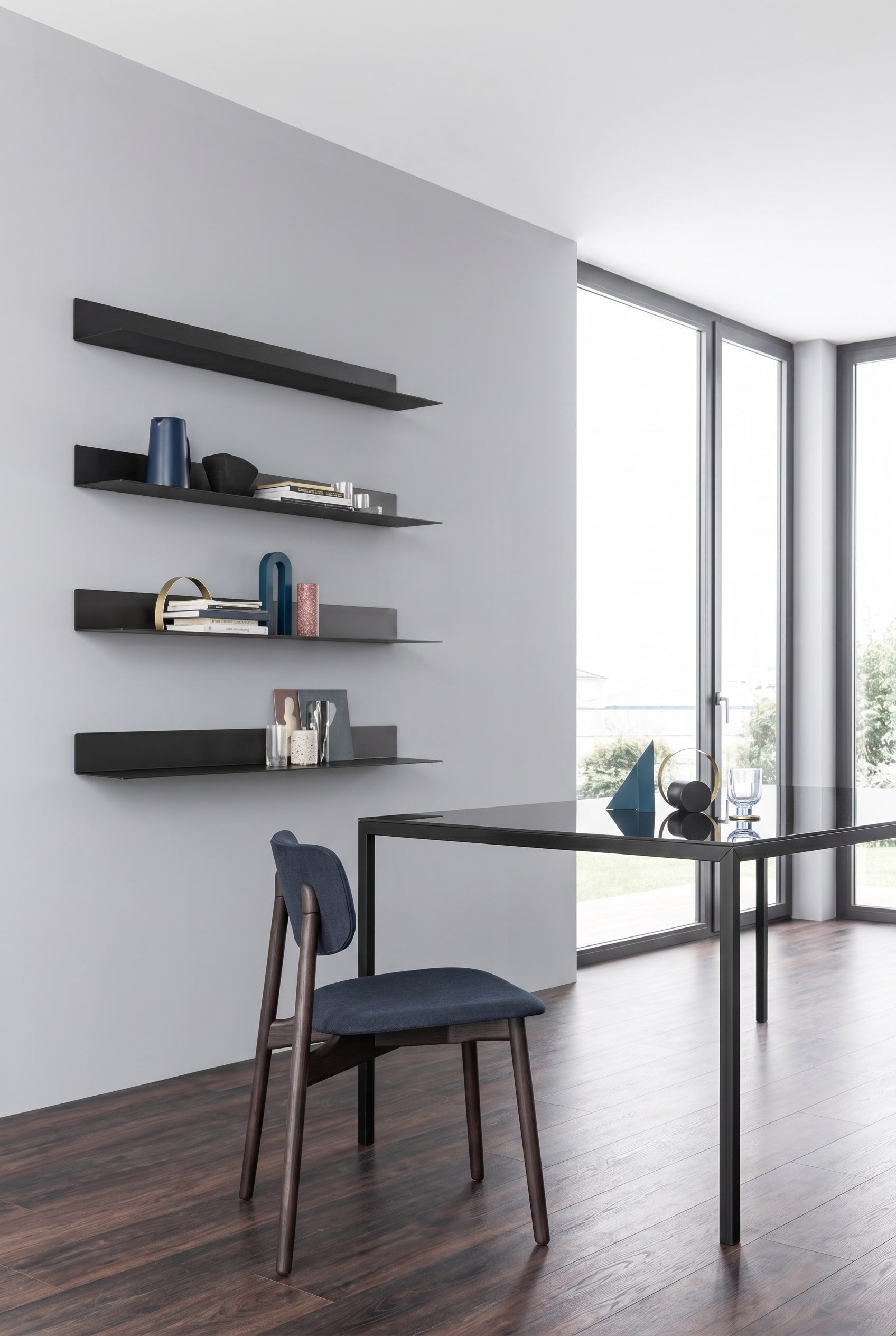 Minimalistische eethoek met filigrane, ultraplatte Novamobili wandrekken Ellie van metaal, asymmetrisch geplaatst tegen een lichtgrijze muur