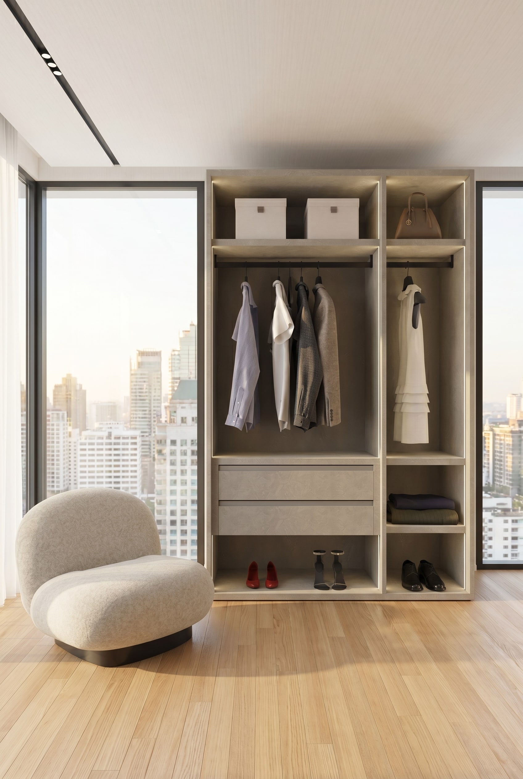 Moderne inloopkast met een frameloos open kastsysteem in gestructureerd greige, hangende linnen overhemden en een loungefauteuil in het warme ochtendlicht
