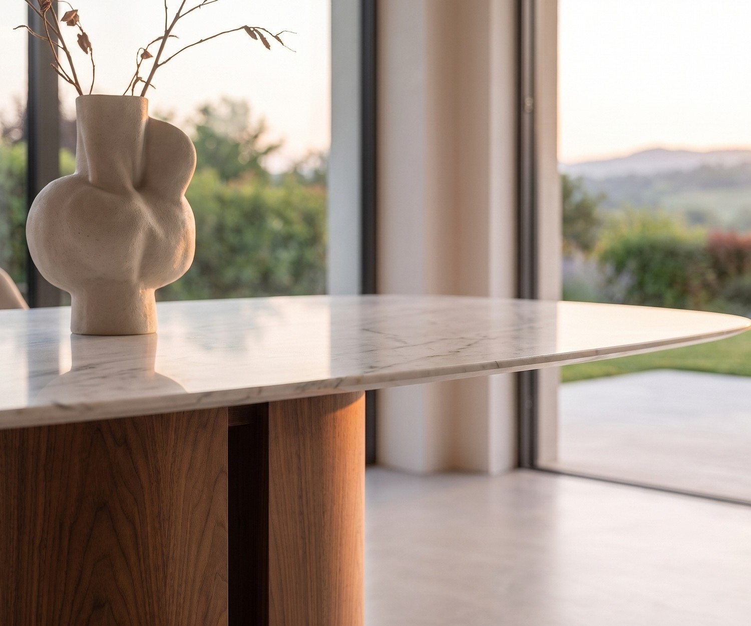 al2 el-it c 001 Dining Table with Marble-Look Top al2 el-it c 001 dining table in a modern dining room featuring a white marble-look top, wooden pedestal base and vase.