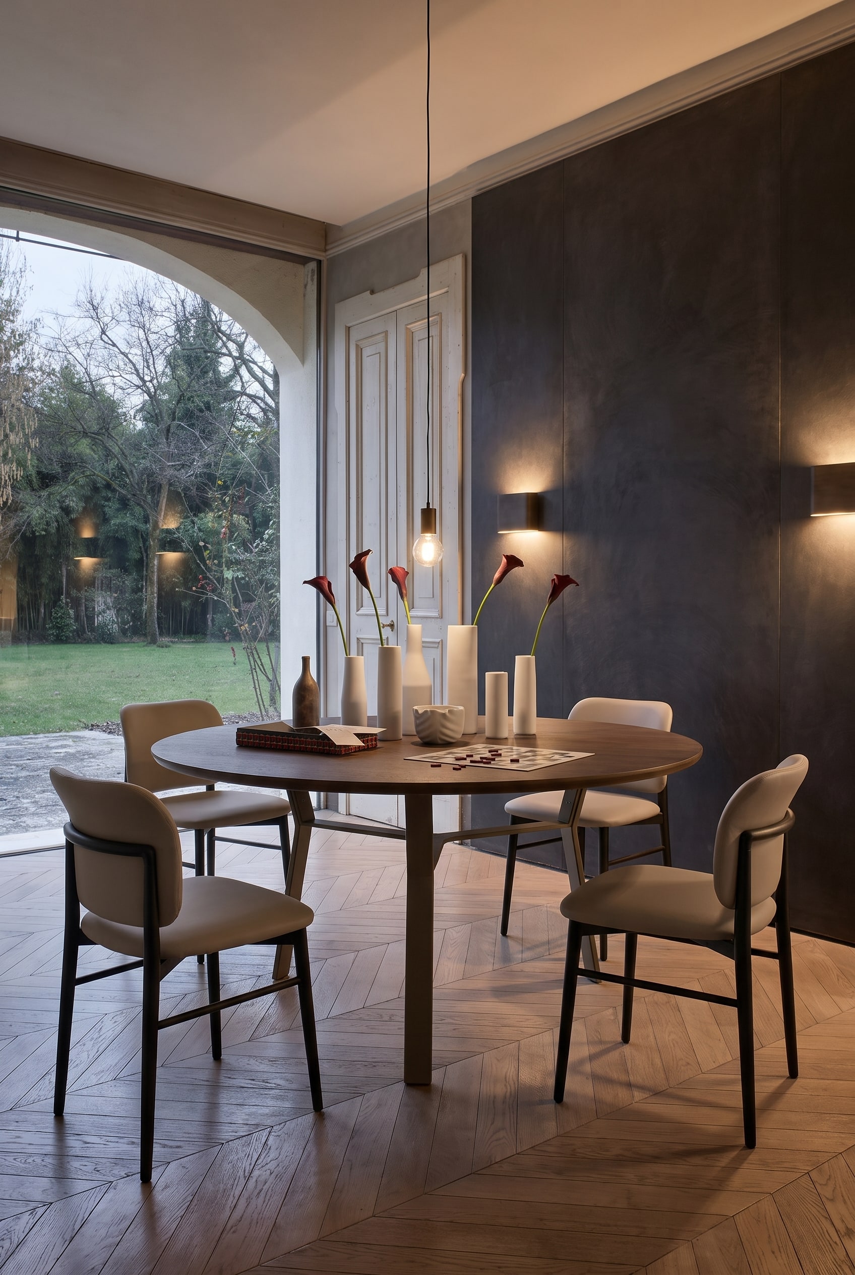 Elegant eetkamer met donkere muur, lange eettafel met metalen onderstel en elegante taupekleurige lederen stoelen
