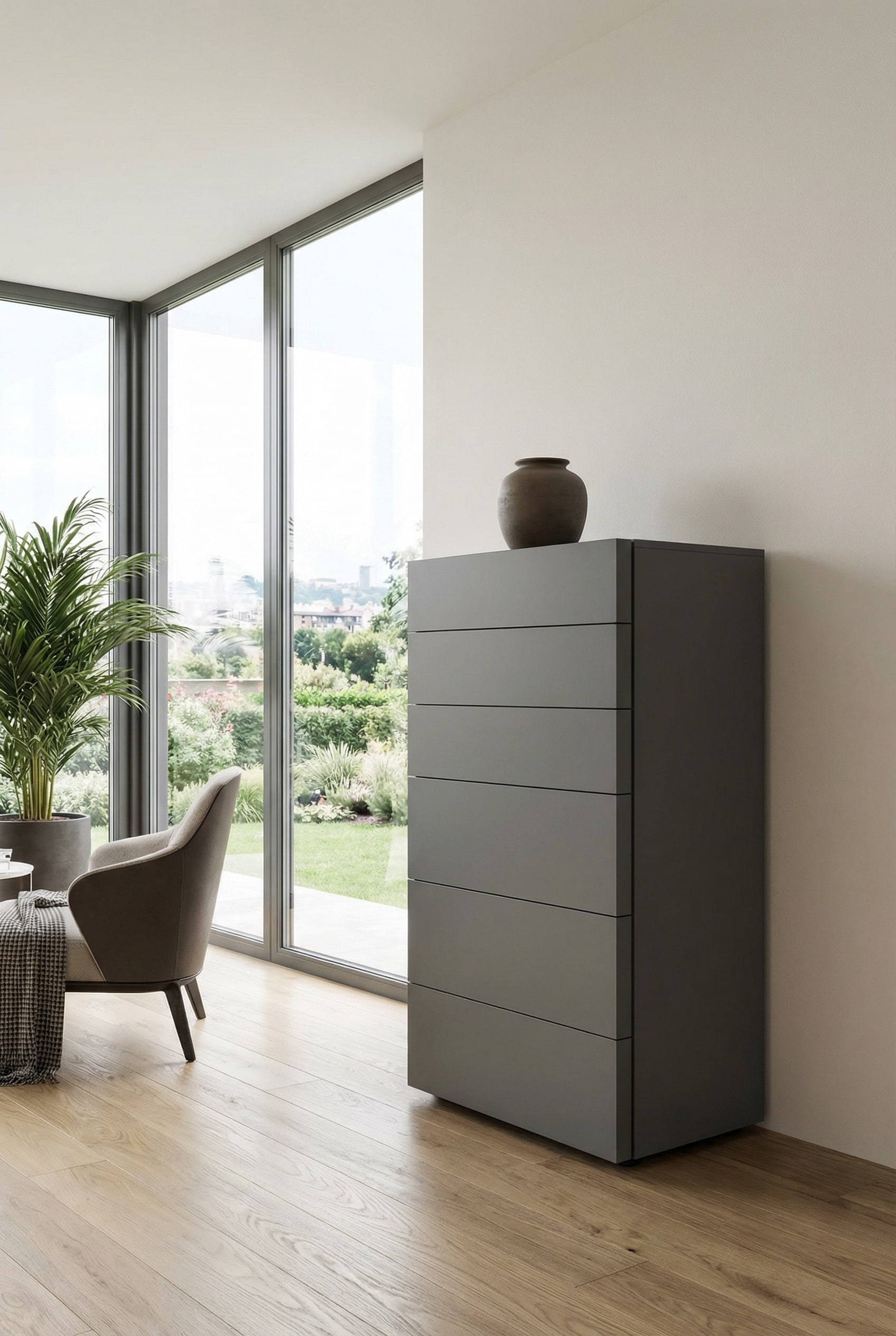 A modern, handleless tall chest of drawers in elegant matte dark grey, staged against a light wall as a minimalist and high-contrast piece of furniture.