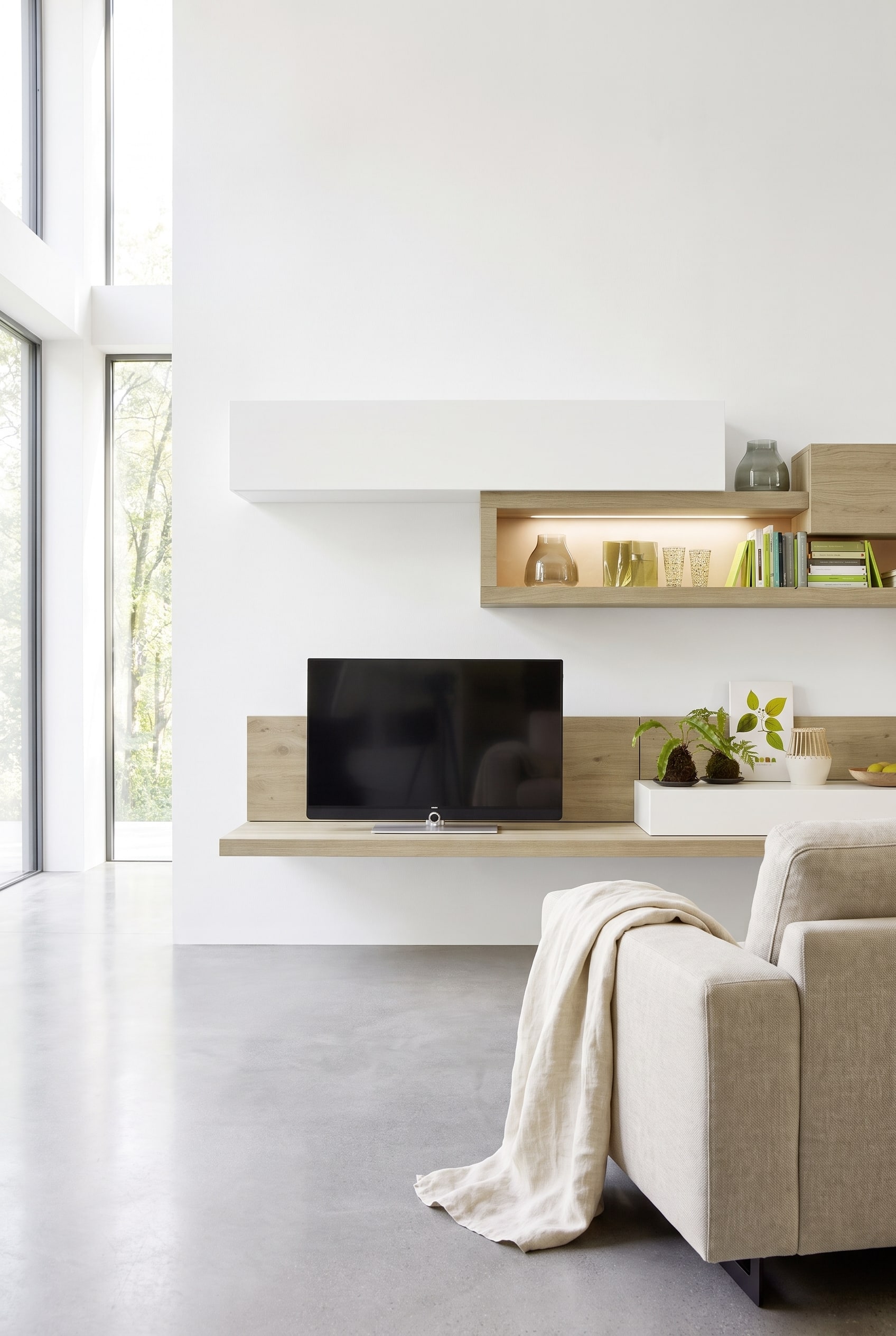 Modern dressoir van hout in wildeiken-look voor een koele betonwand, gecombineerd met een gestructureerde linnen plaid.