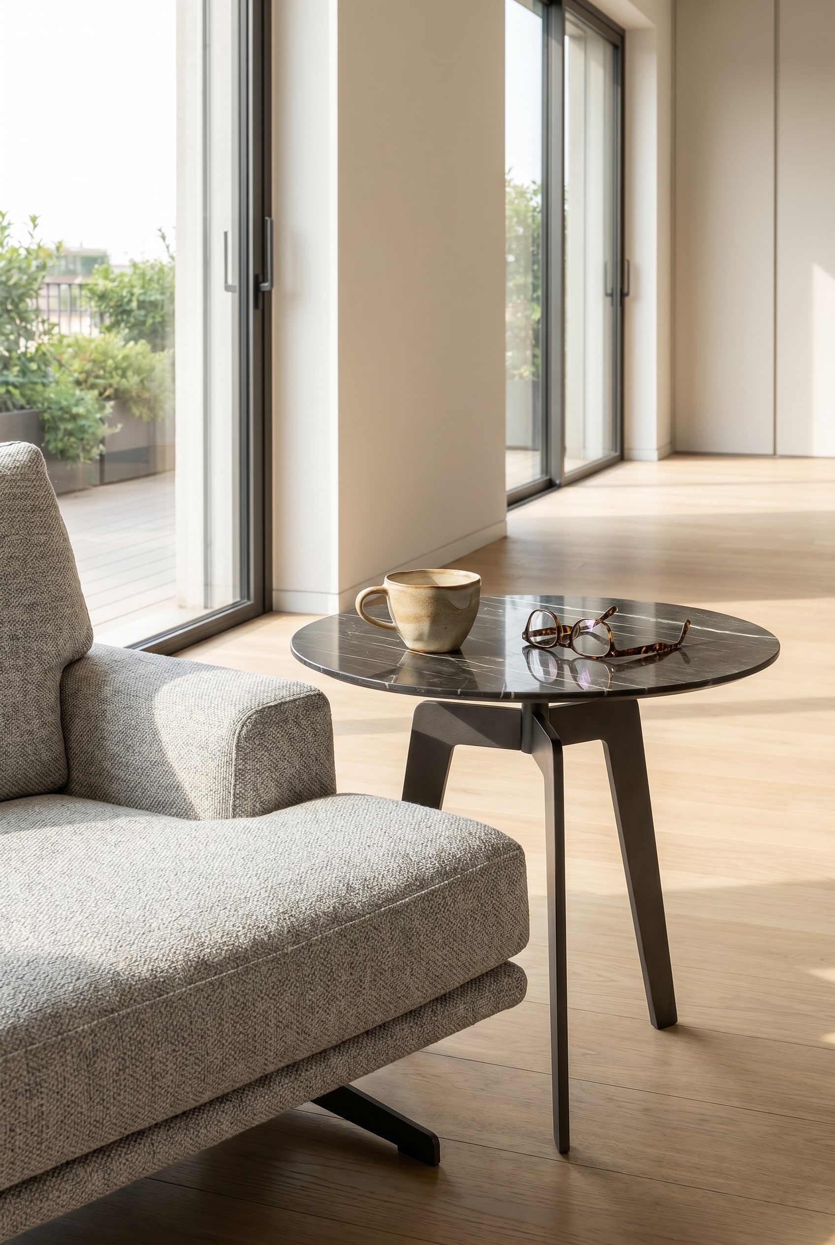 Tavolino minimalista Lotus effetto marmo accanto a una poltrona lounge con una tazza di caffè bianca