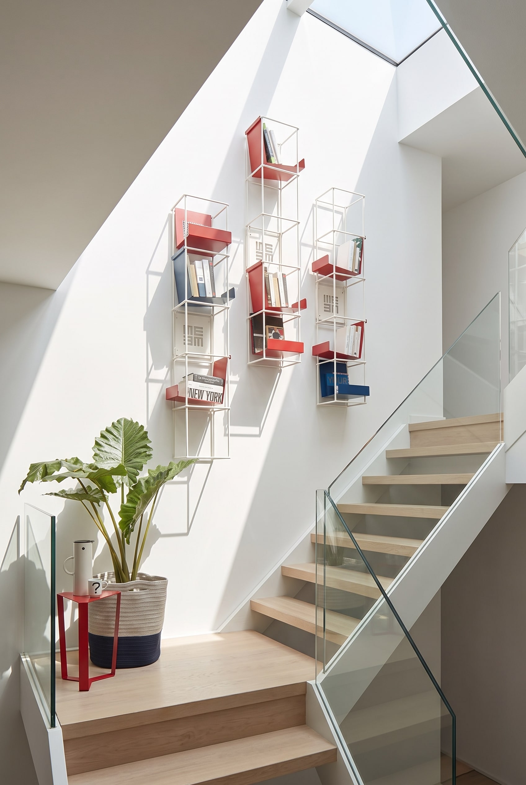 Modulair, open wandrek Livitalia Tetris aan de witte muur van een modern trappenhuis, gevuld met boeken en decoratie