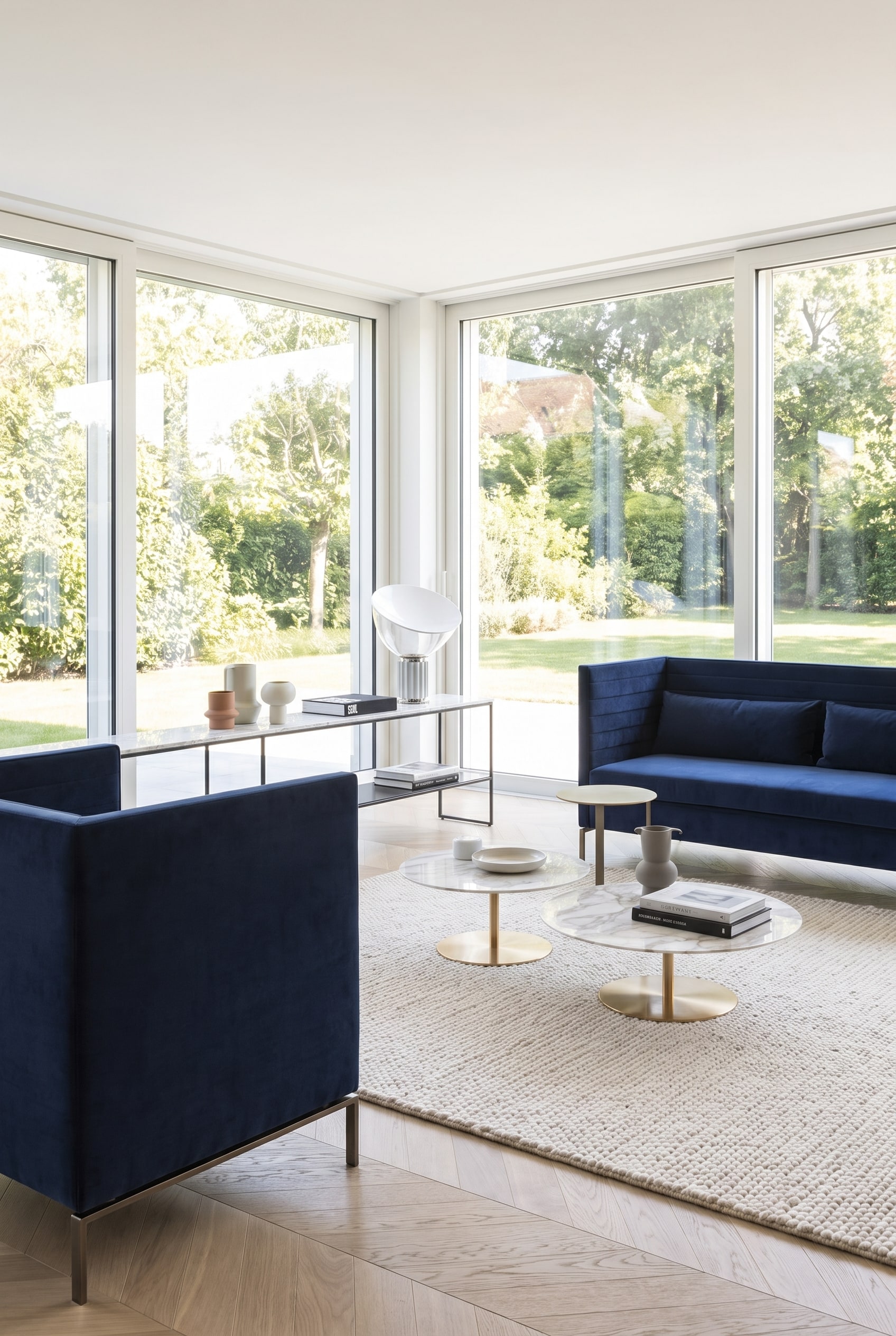 Ruim ogende woonkamer met een donkerblauwe, filigrane bank op slanke metalen sledepoten, die de lichte houten vloer zichtbaar laat.