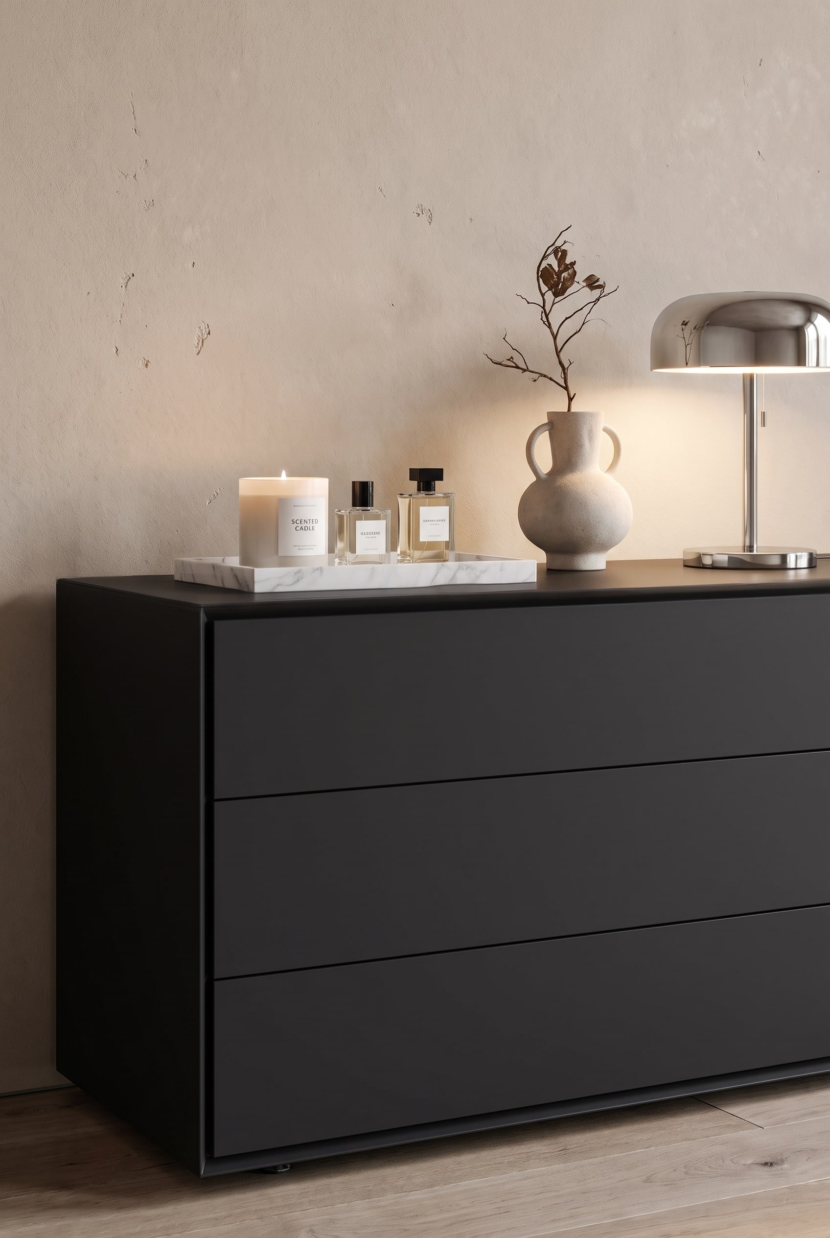 Cassettiera di design opaca nella zona giorno-notte, con volumi illustrati impilati, un vaso scultoreo e una piccola lampada da tavolo
