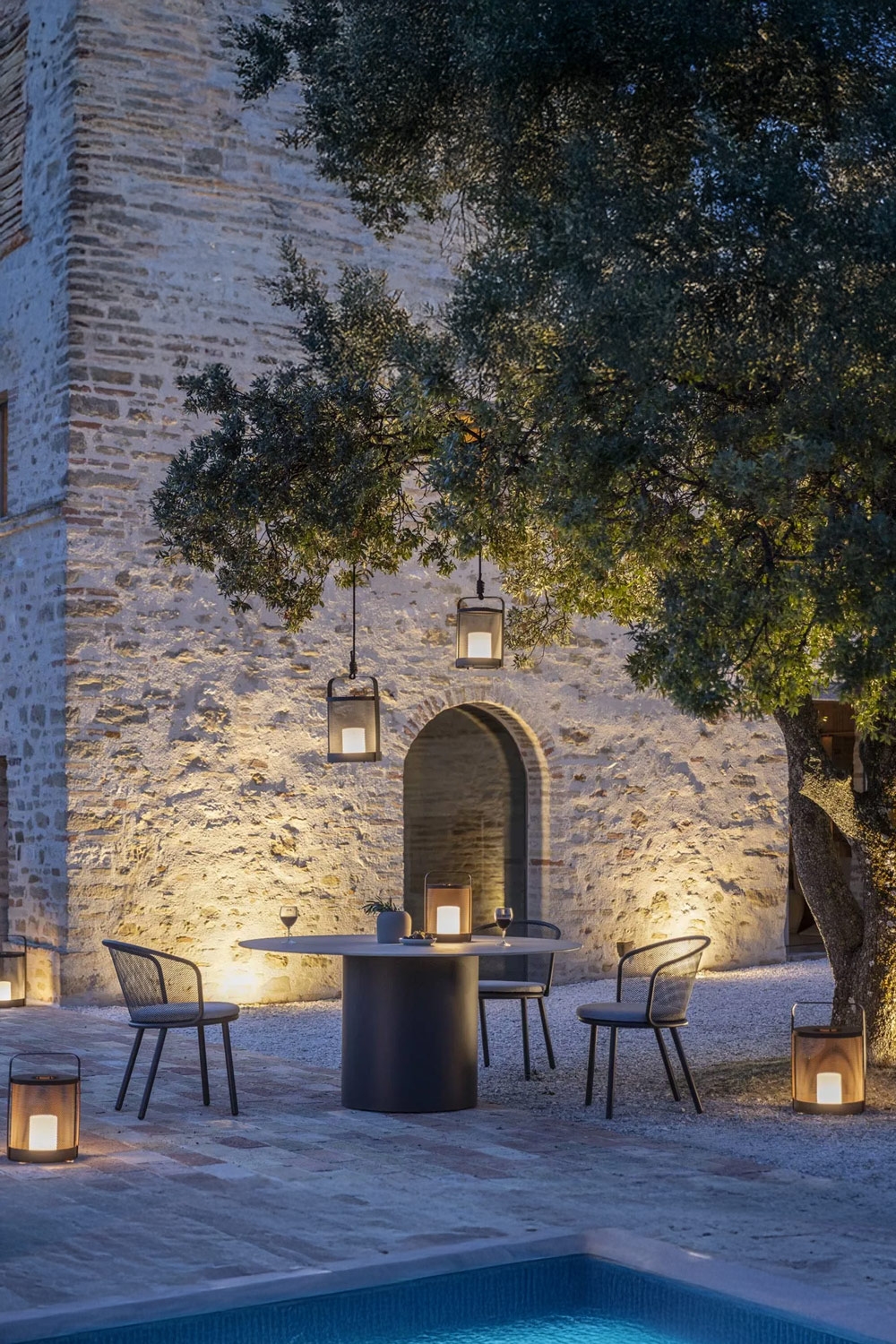 stimmungsvoll-beleuchtete-terrasse-mit-modernem-tisch-aus-edelstahl-und-keramik-und-gartenstuehlen-aus-edelstahl