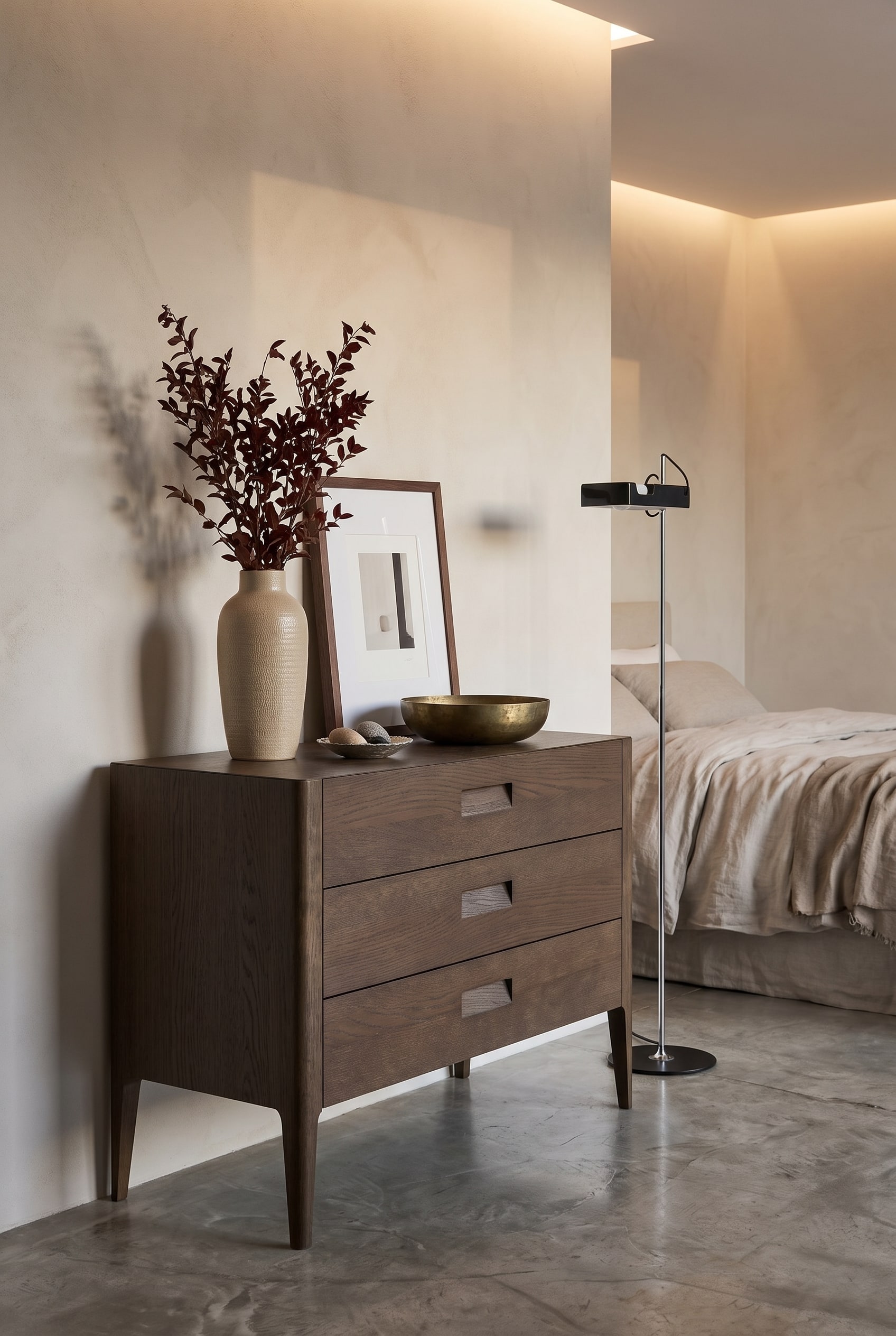 Modern bedroom with dark oak dresser, tall ceramic vase, medium-sized picture frame, and flat brass bowl in warm light