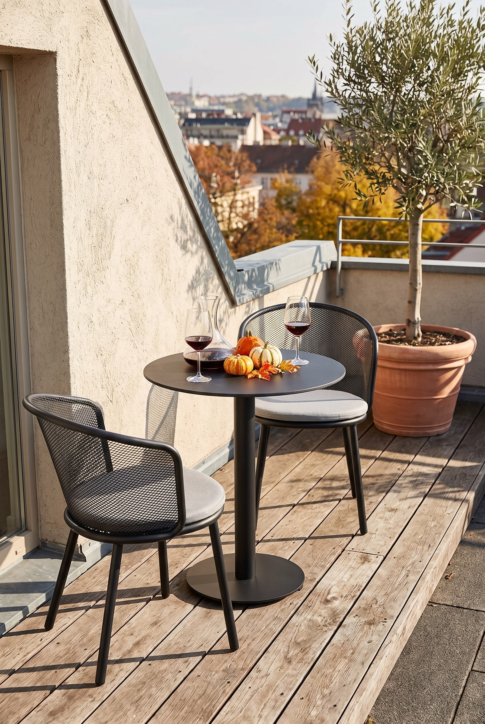 Table de bistrot ronde noire avec pied central élancé sur une étroite terrasse de toit en bois