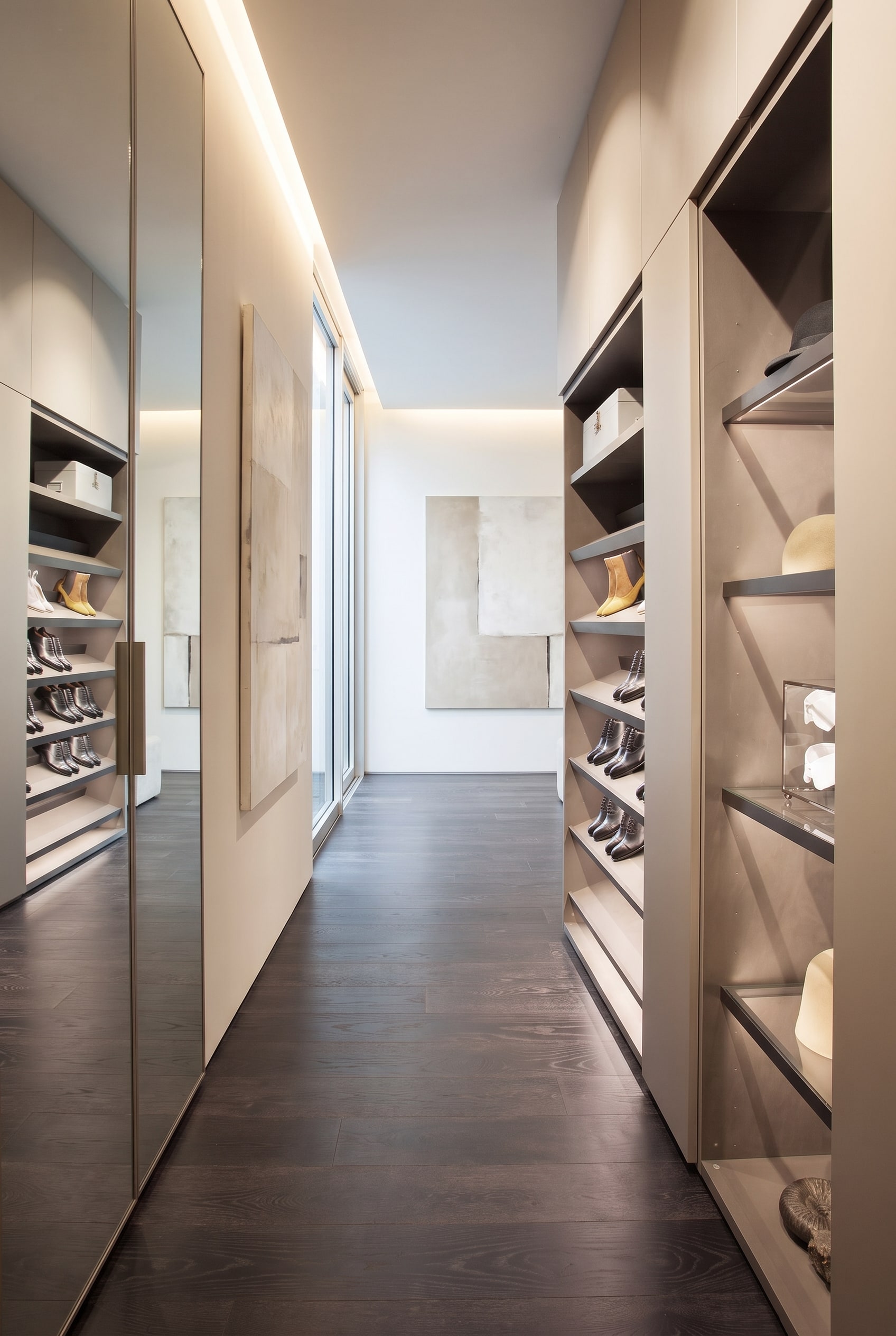 Una scarpiera moderna leggermente aperta nell'ingresso, che mostra al suo interno ripiani inclinati con illuminazione LED integrata.