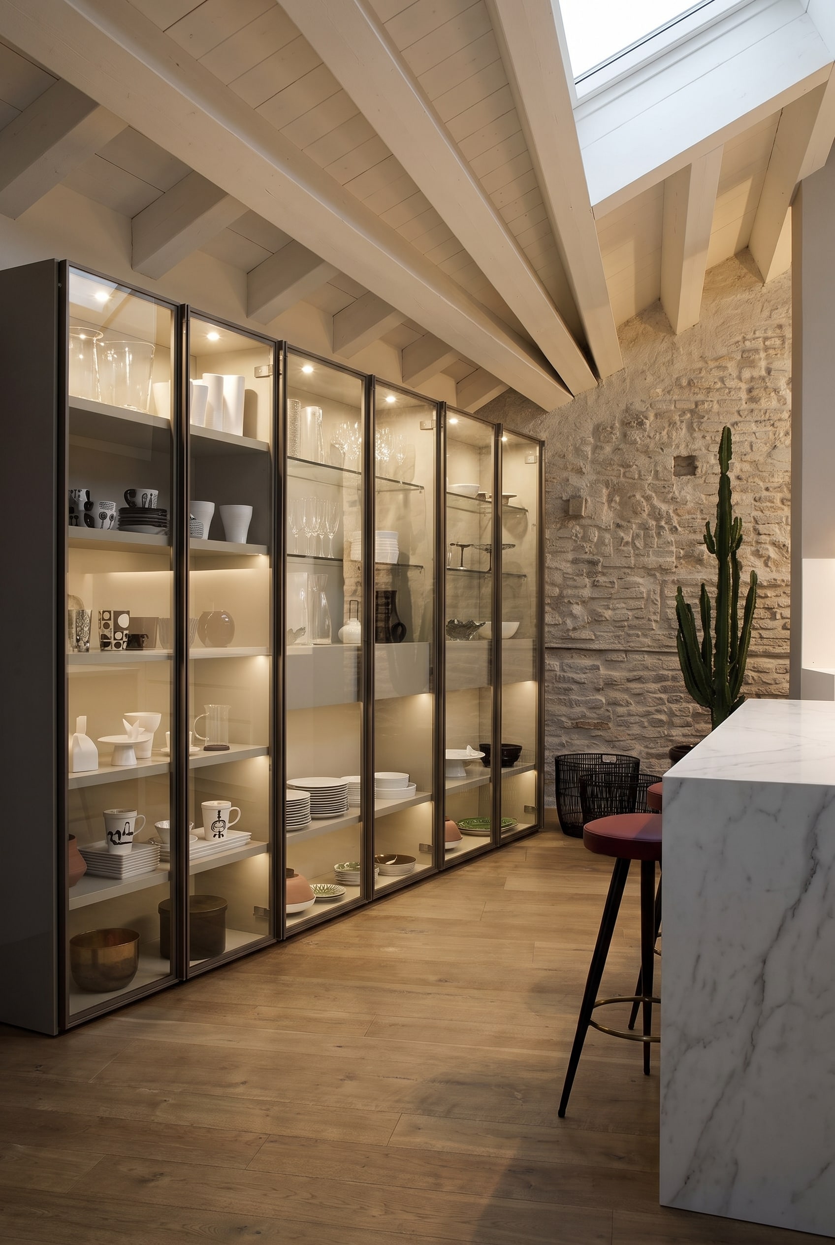 Tall glass display cabinet with a fine metal frame and soft LED interior lighting in an elegant dining room