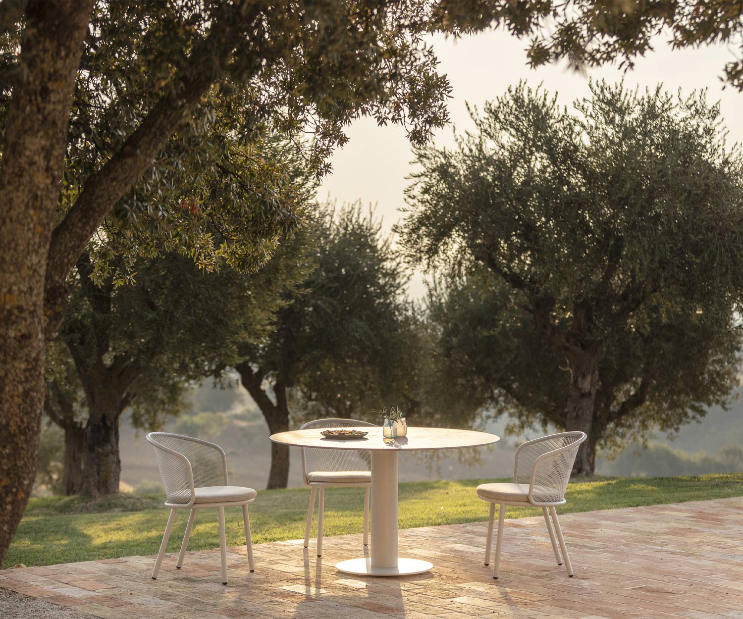 Minimalistischer Todus Branta Gartentisch mit Frühstücksgedeck unter Bäumen
