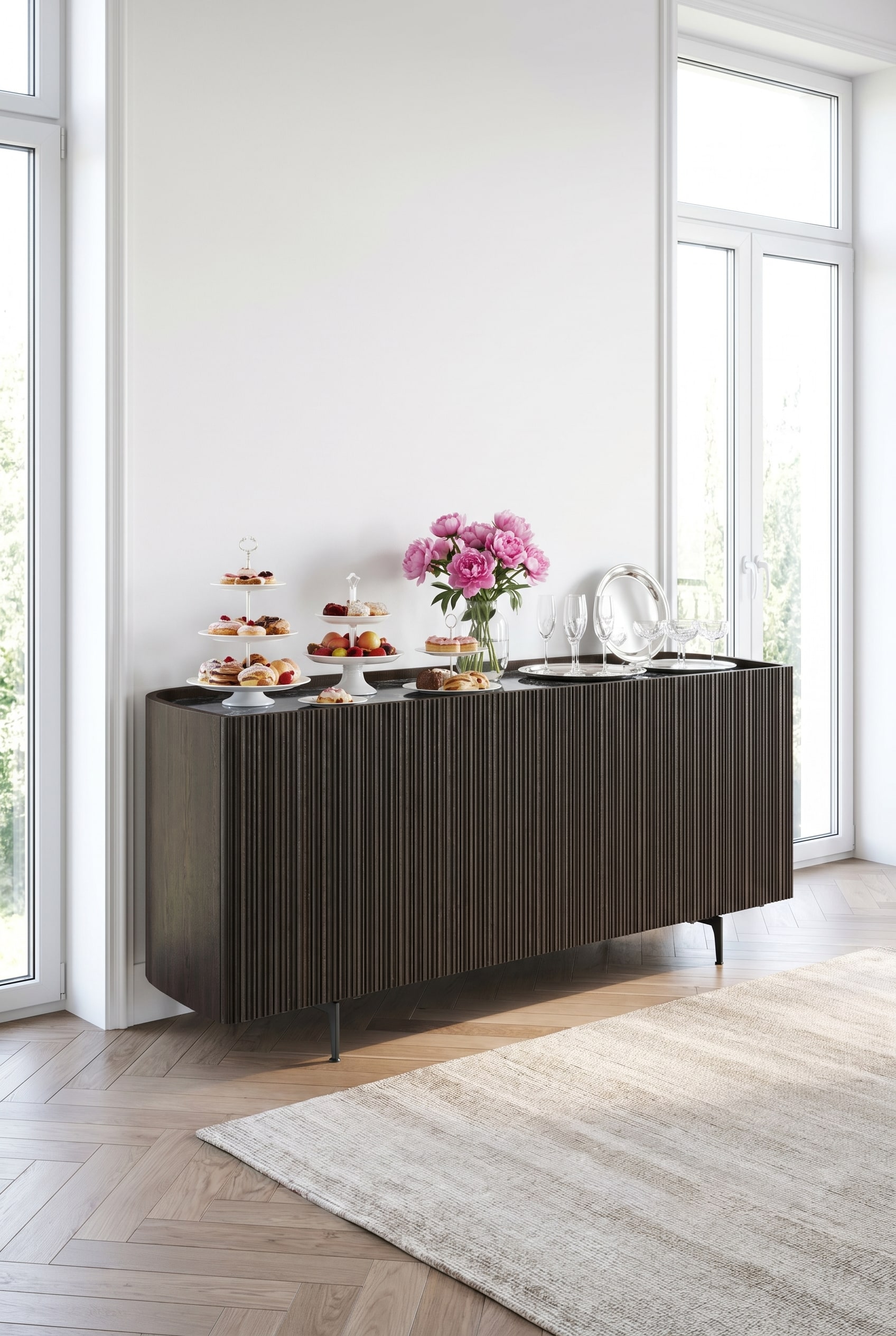 Donker Novamobili Bay Sideboard met afgeronde hoeken en geribbelde voorkant in een lichte ruimte, gedecoreerd met witte porseleinen borden en roze pioenrozen.