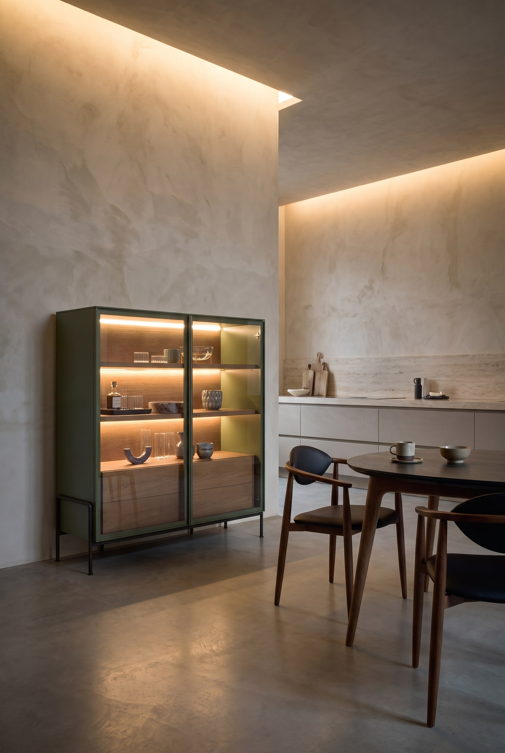 Elegante woonkeuken met een hoog highboard met afgeronde hoeken, daarnaast een minimalistische eettafel met stoelen