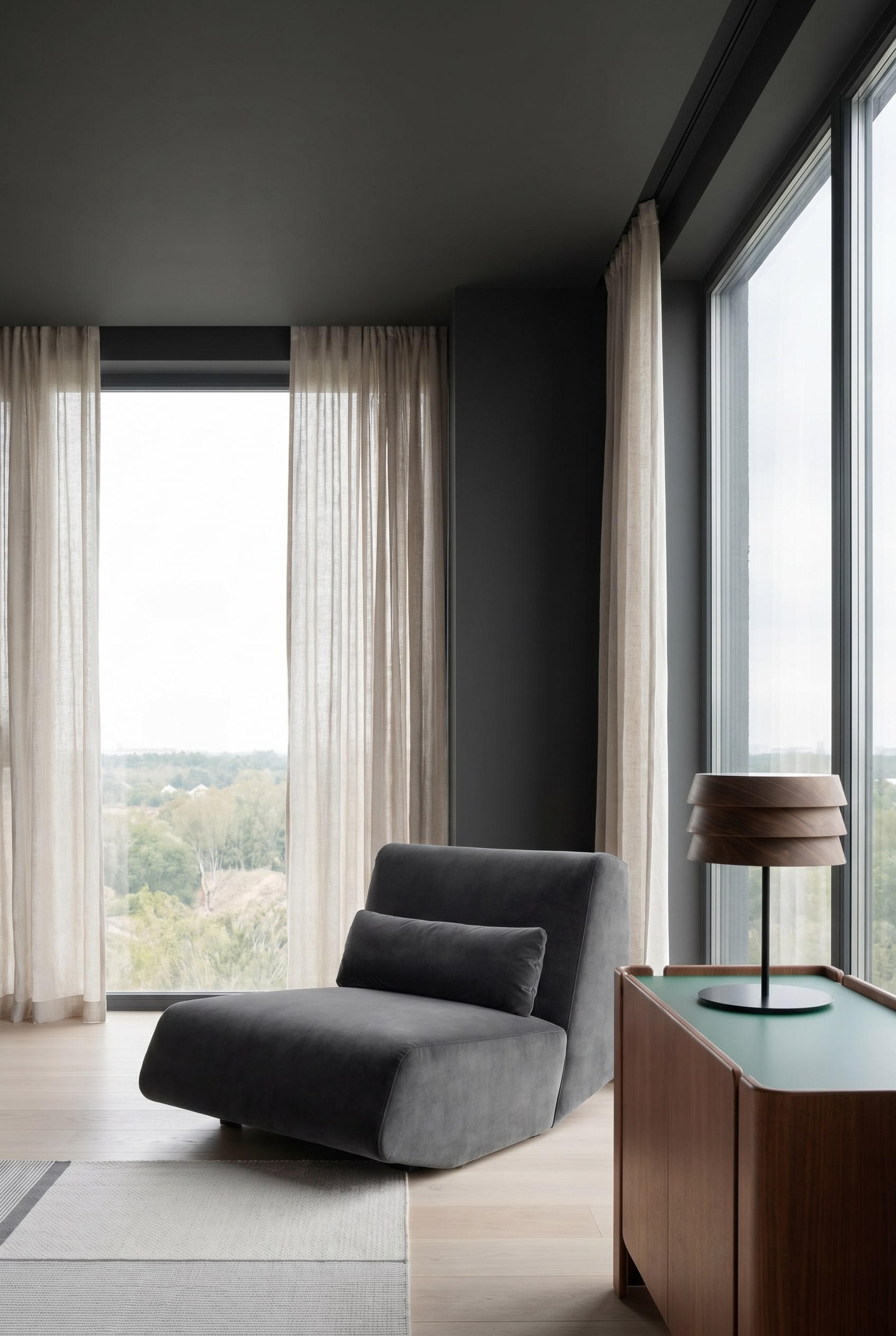Soggiorno moderno con poltrona lounge profonda e vellutata in grigio scuro e pareti dipinte in modo uniforme e scuro