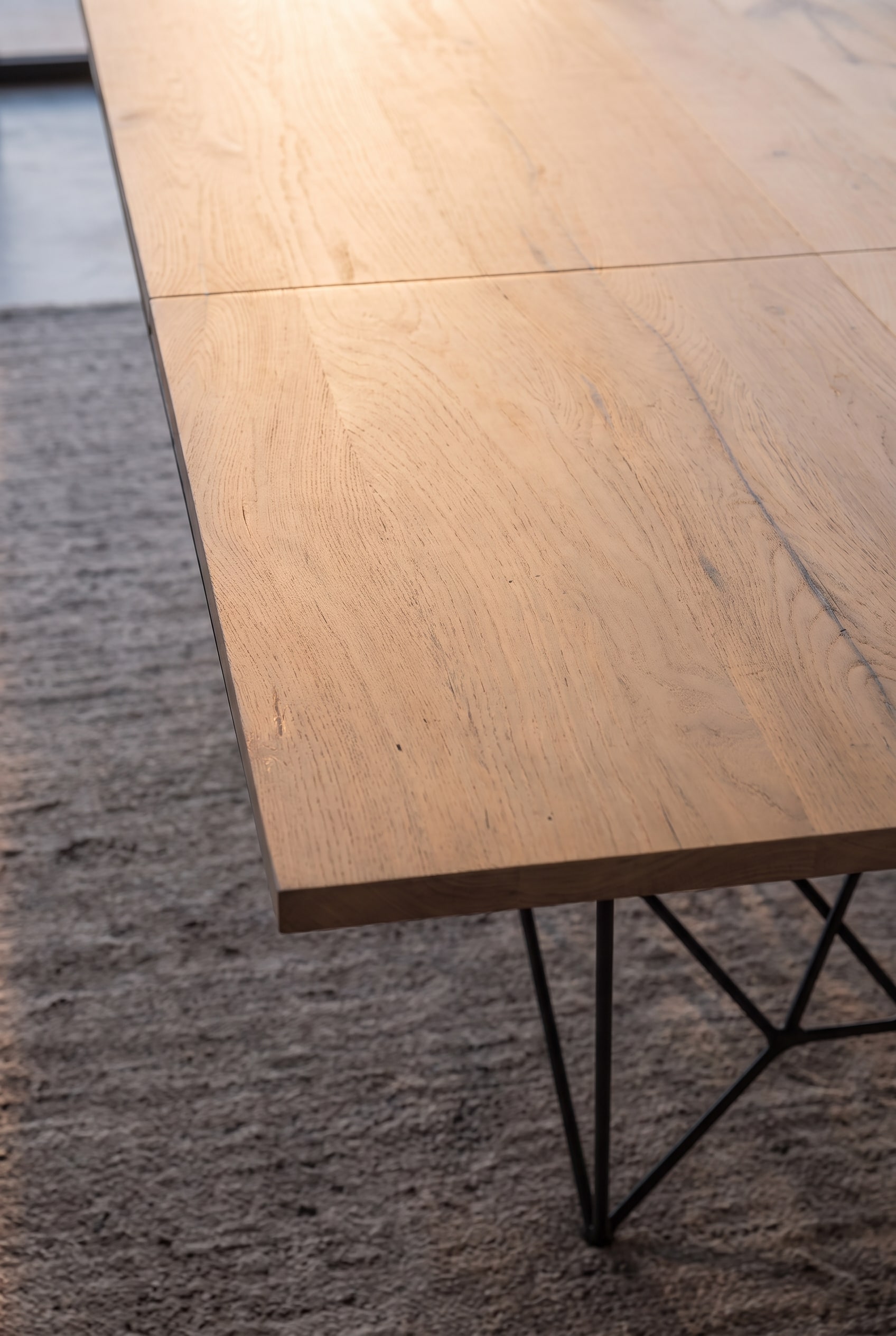 Detailansicht der Holzkante und des schwarzen Metallgestells des Ozzio Fil8 Esstisches.