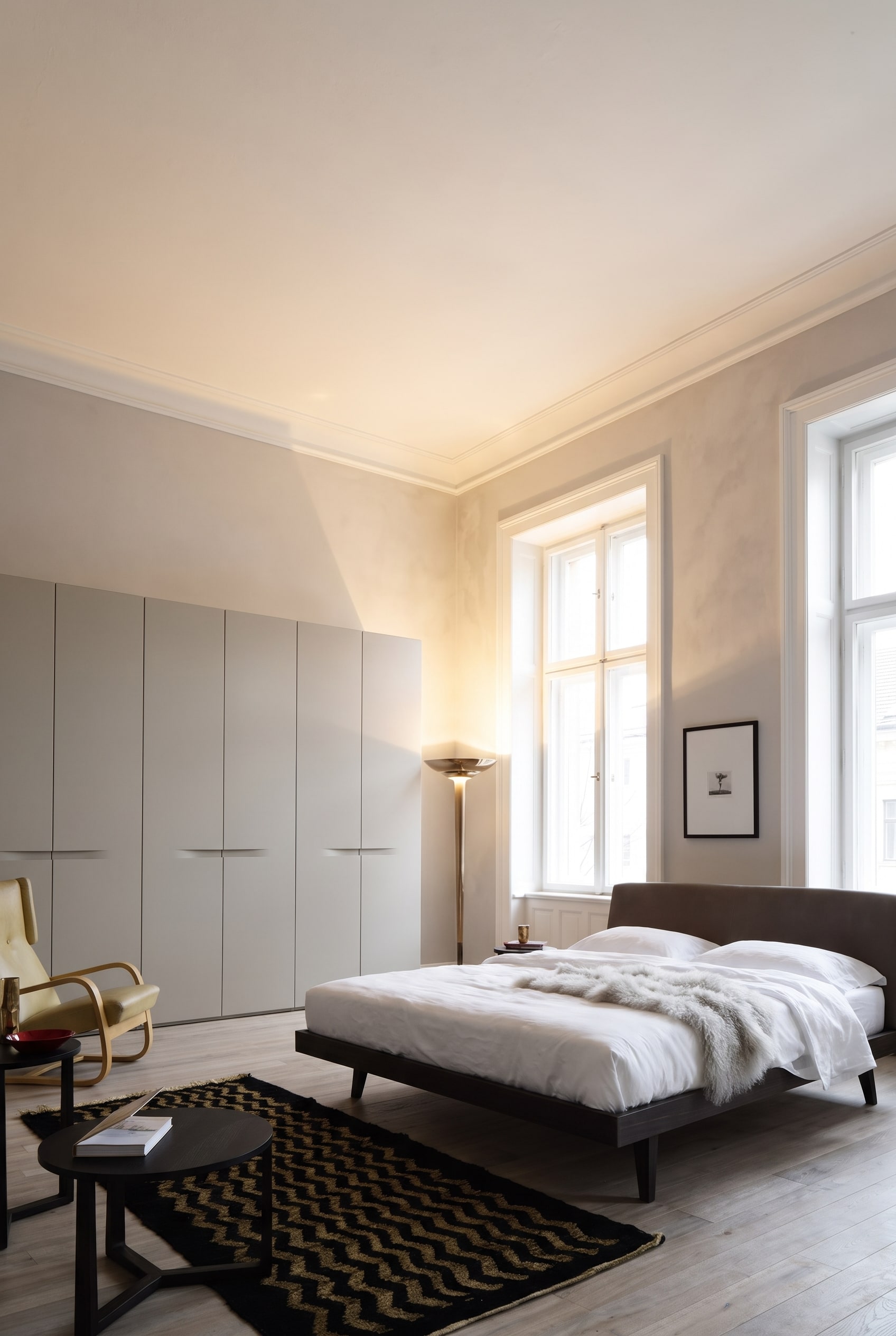 Elegant old building bedroom with a ceiling-high, matte wardrobe, wooden bed, and warm textiles