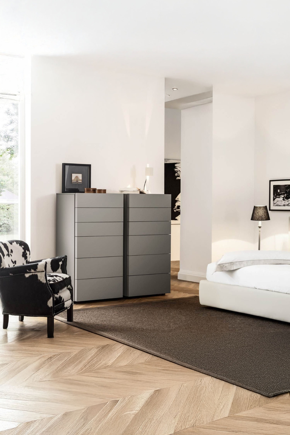 moderne-schubladenkommode-mit-grifflosen-fronten-zwischen-einem-eleganten-bett-und-extravaganten-sessel