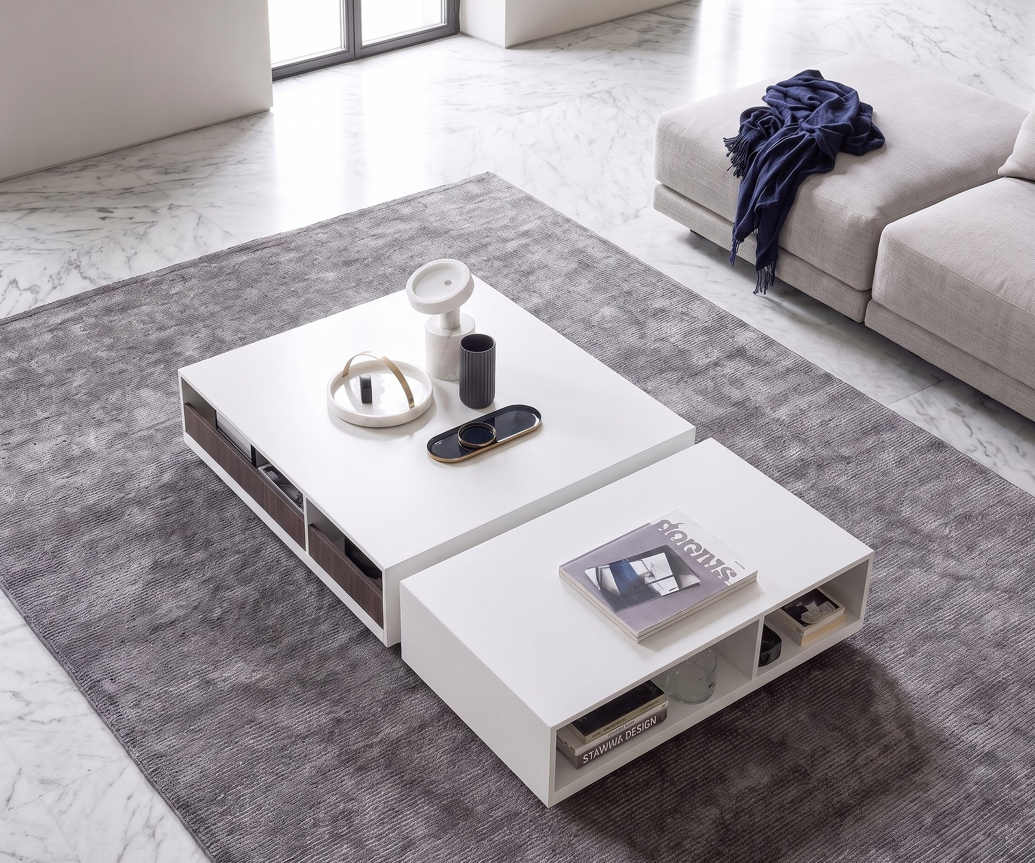 Couchtisch Seven von Novamobili mit Stauraum für das Wohnzimmer. Weißer, minimalistischer Tisch auf grauem Teppich.
