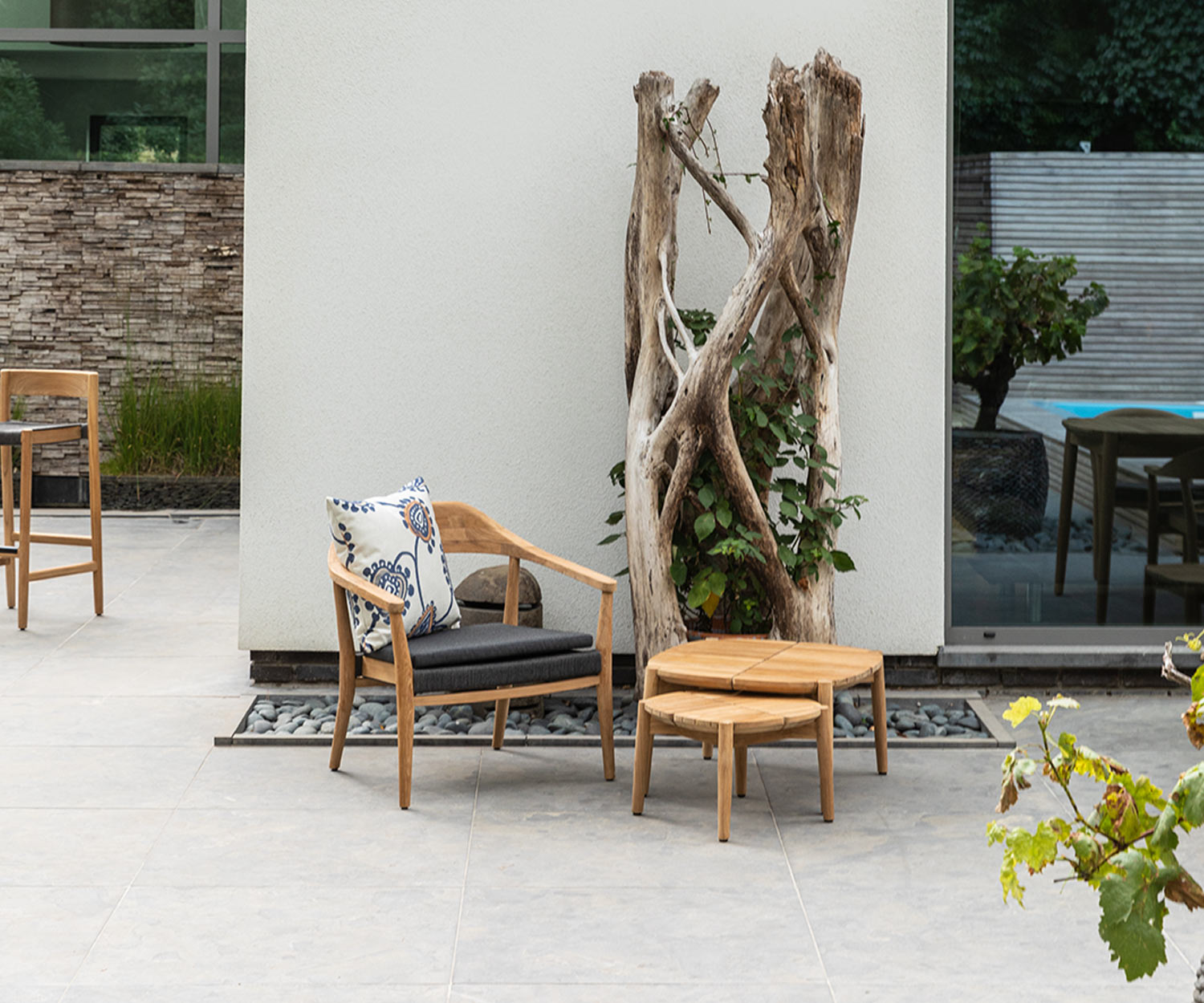 Moderner Oasiq Copenhagen Lounger mit Beistelltischen auf Terrasse neben Baum Moderner Oasiq Copenhagen Lounger mit Beistelltischen auf Terrasse neben Baum