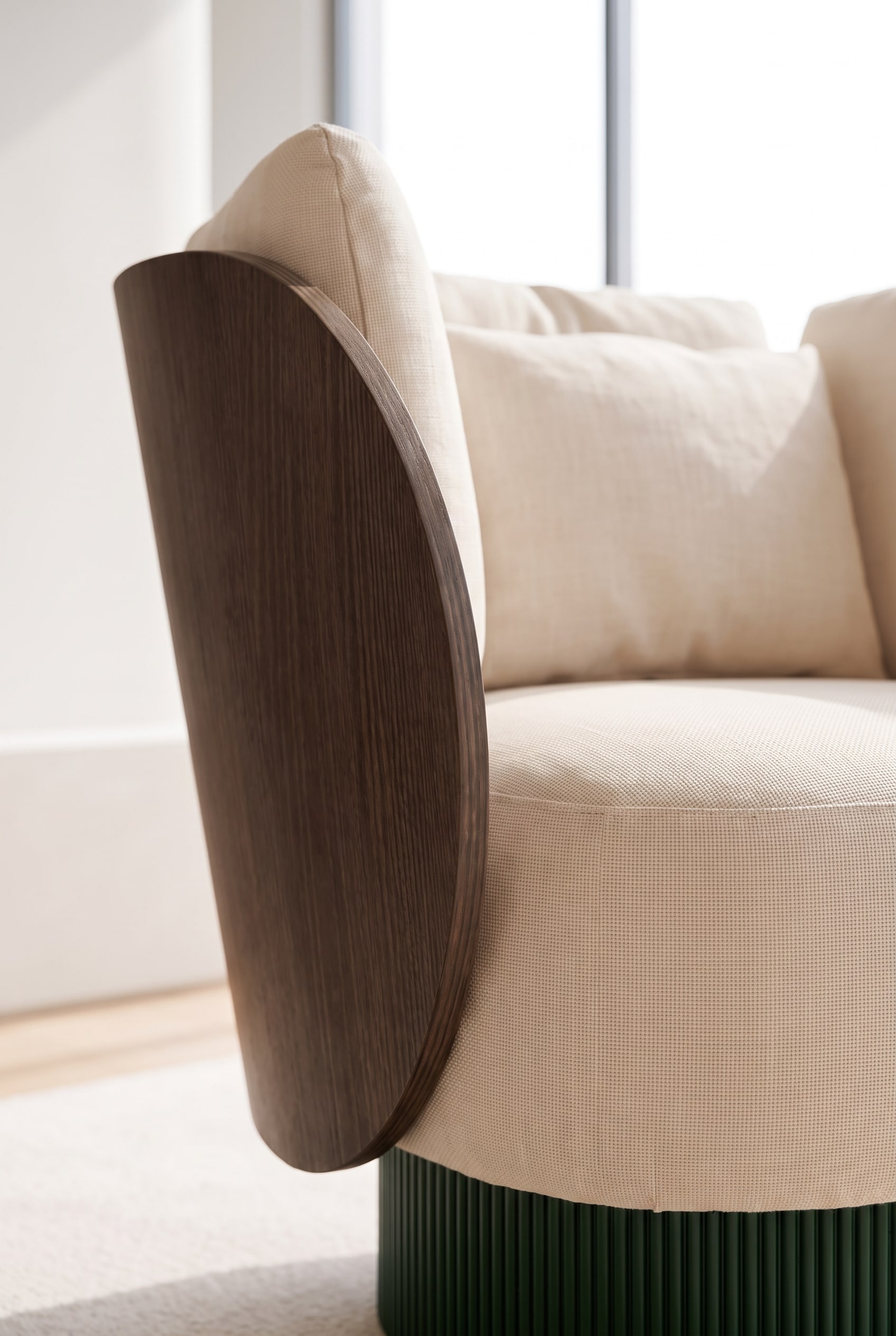 Close-up van de materiaalcombinatie van gebogen hout, geribbelde sokkel en beige premiumstof.