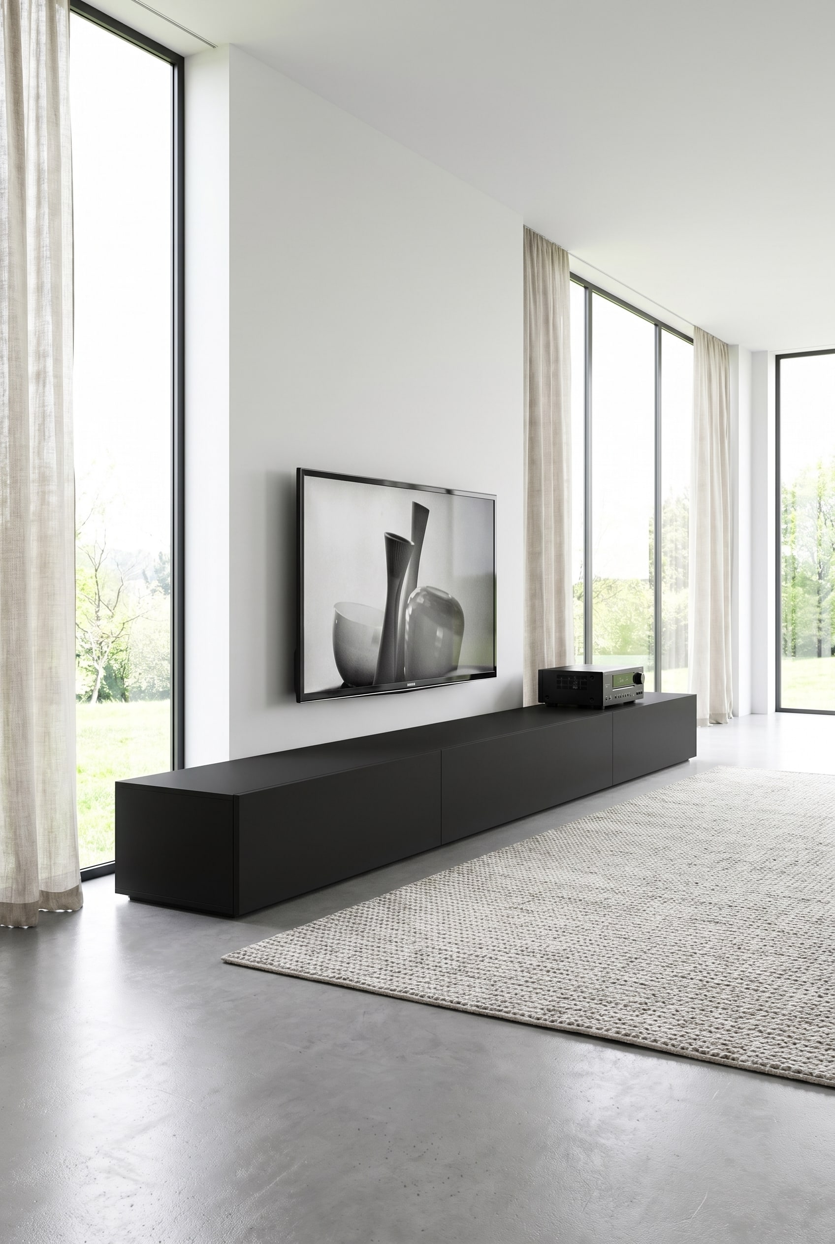 Extremely long, matte black lowboard in a bright, minimalist living room
