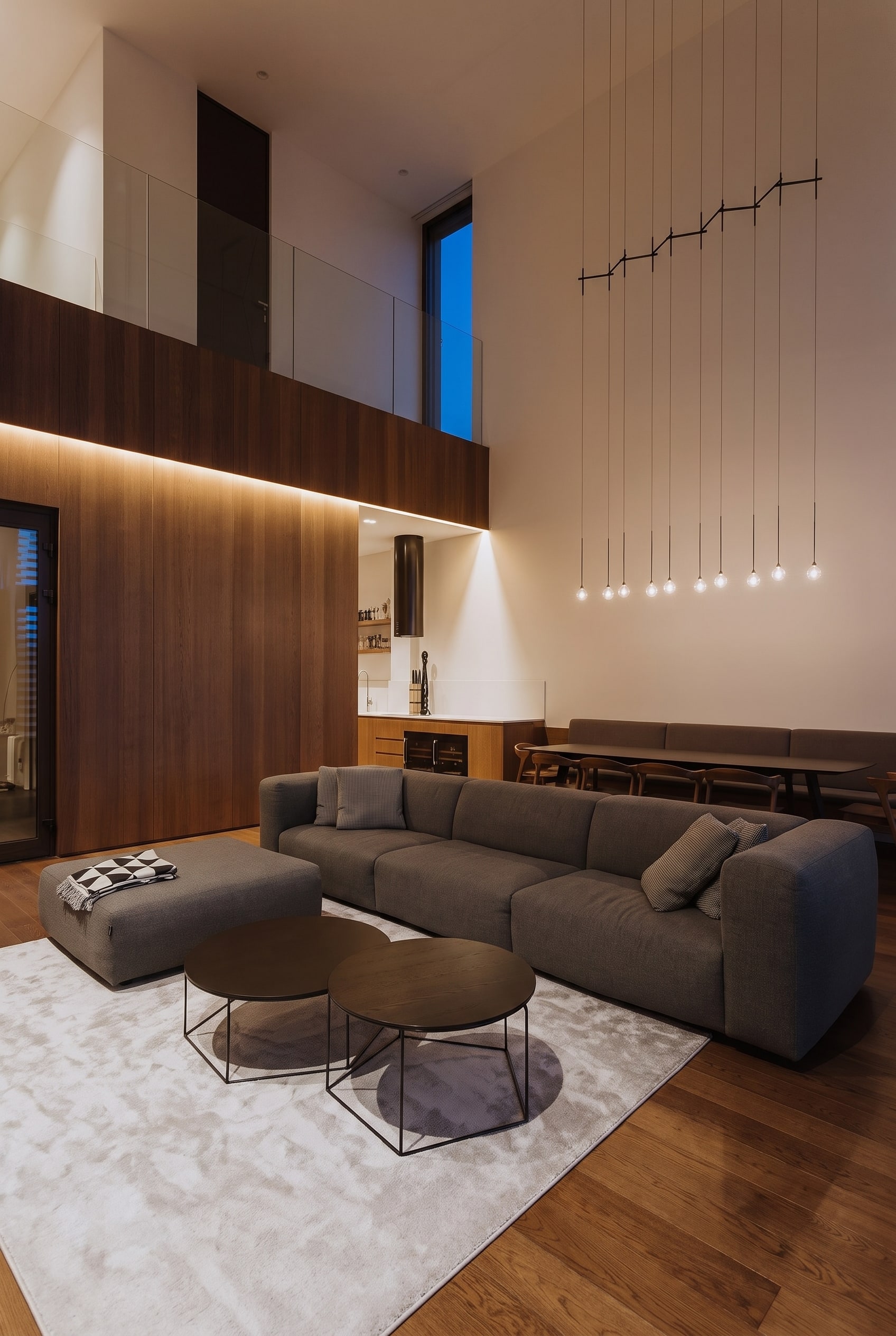 Een vrijstaande, volumineuze leren bank met filigrane metalen poten, die als visueel anker in een lichtdoorstroomde woonkamer staat.