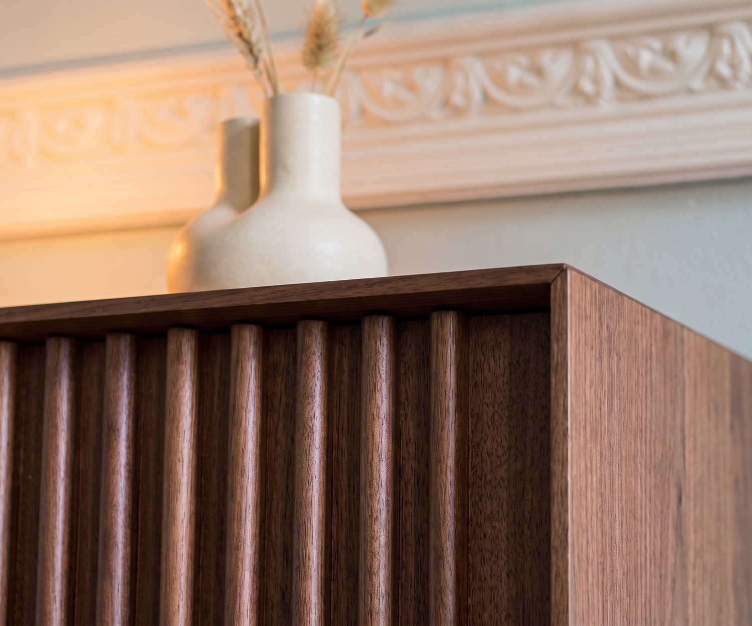 al2 ka-bera 003 A Design Sideboard aus Walnuss Design Sideboard al2 ka-bera 003 A aus Walnuss mit Holz-Lamellen, Detailansicht mit Vase im Wohnzimmer.