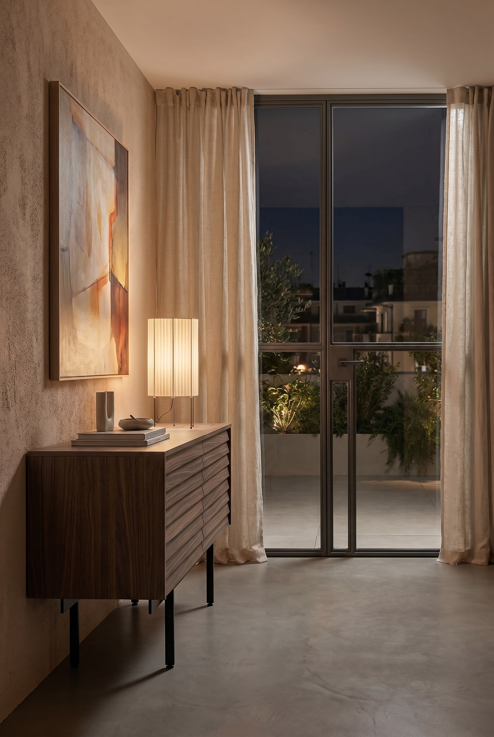 Gezellige slaapkamer met laag houten dressoir en tafellamp met geplisseerde stoffen kap in beige bij warm licht