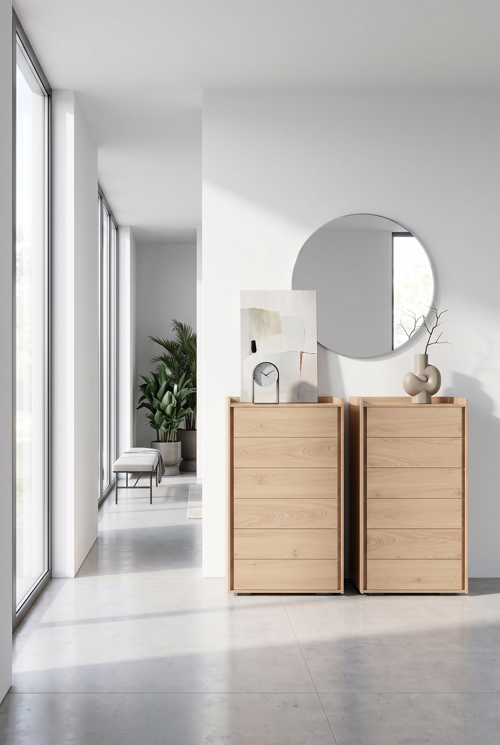Cassettiera alta stretta in legno chiaro nell'ingresso, sul piano superiore un elegante orologio da tavolo e un quadro minimalista appoggiato
