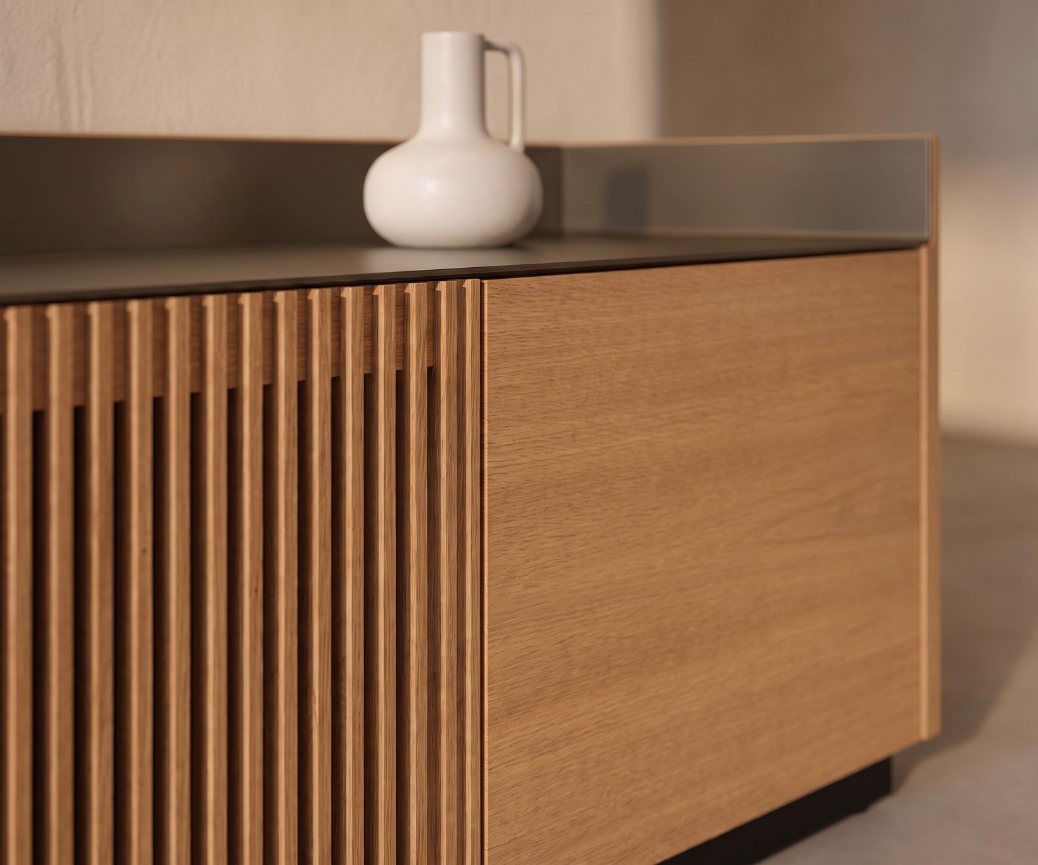 Punt Stockholm TV Lowboard aus Eiche mit Lamellenfront und Alu-Deckplatte im modernen Wohnzimmer mit Vase.
