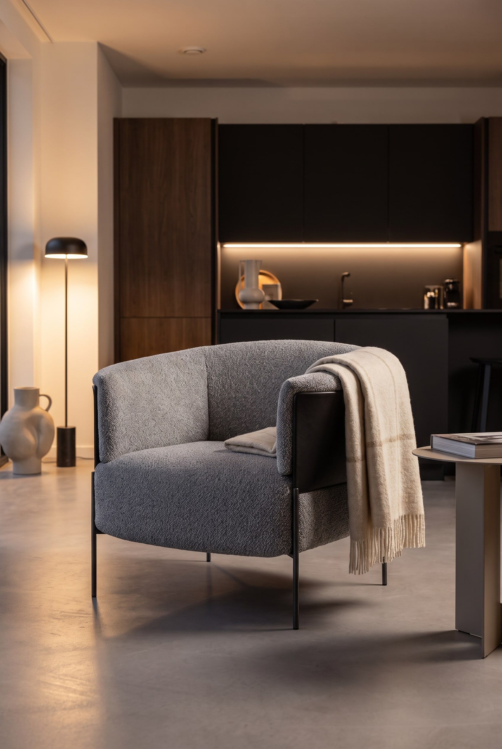 Lichtgrijze gestoffeerde fauteuil met ronde rugleuning als zacht contrast in de ruimte