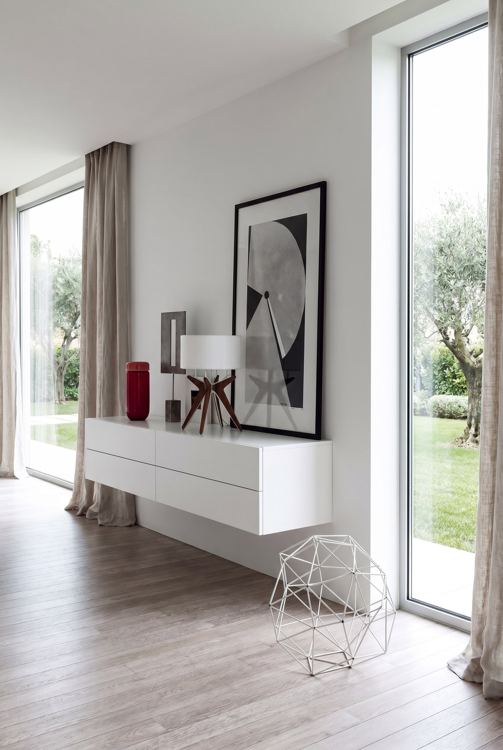 Zona ingresso minimalista con cassettiera sospesa Novamobili Easy 4 cassetti di colore bianco puro e una scultura astratta