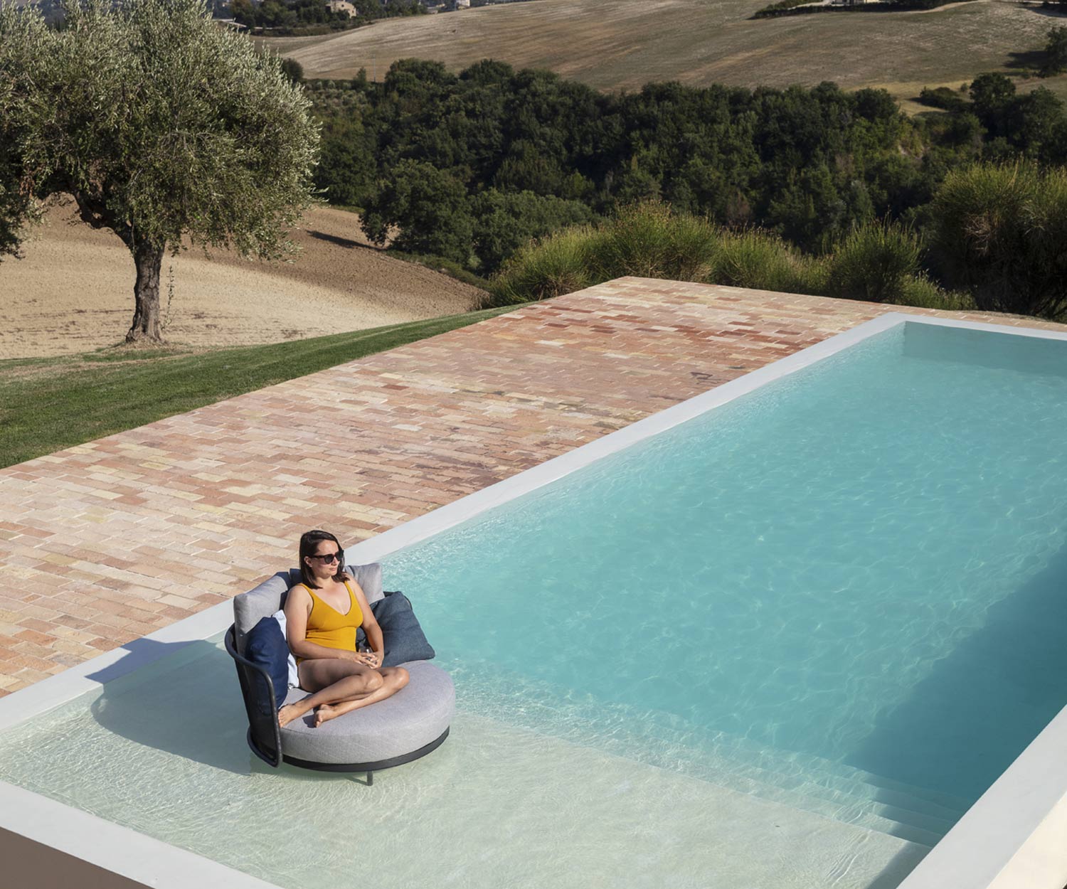 Durable Baza Round garden lounge from Todus with feet in the pool Durable Baza Round garden lounge from Todus with feet in the pool