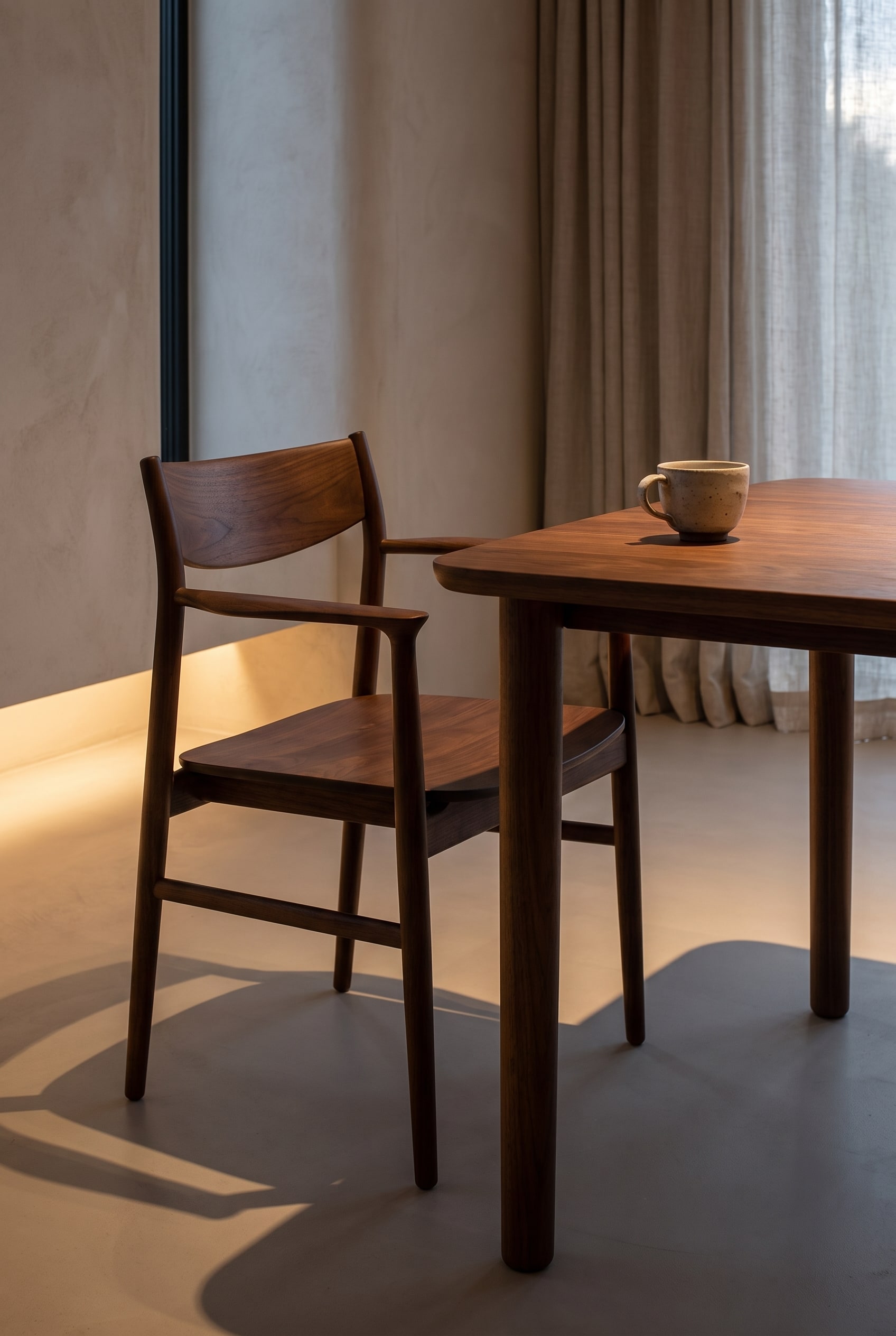 Detailopname van een donkerbruine houten stoel met een plat silhouet en een haptische zitting aan de eettafel