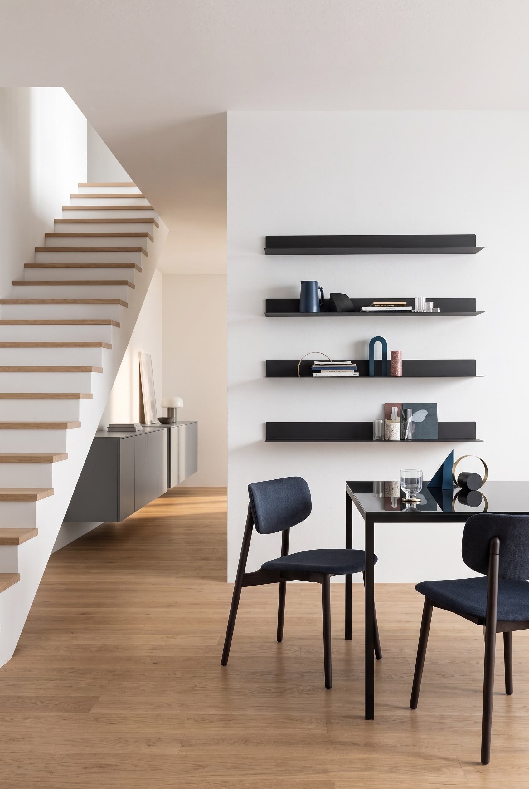 Een elegant Punt Rio Sideboard met gesloten fronten in de doorgang naast een moderne houten trap.