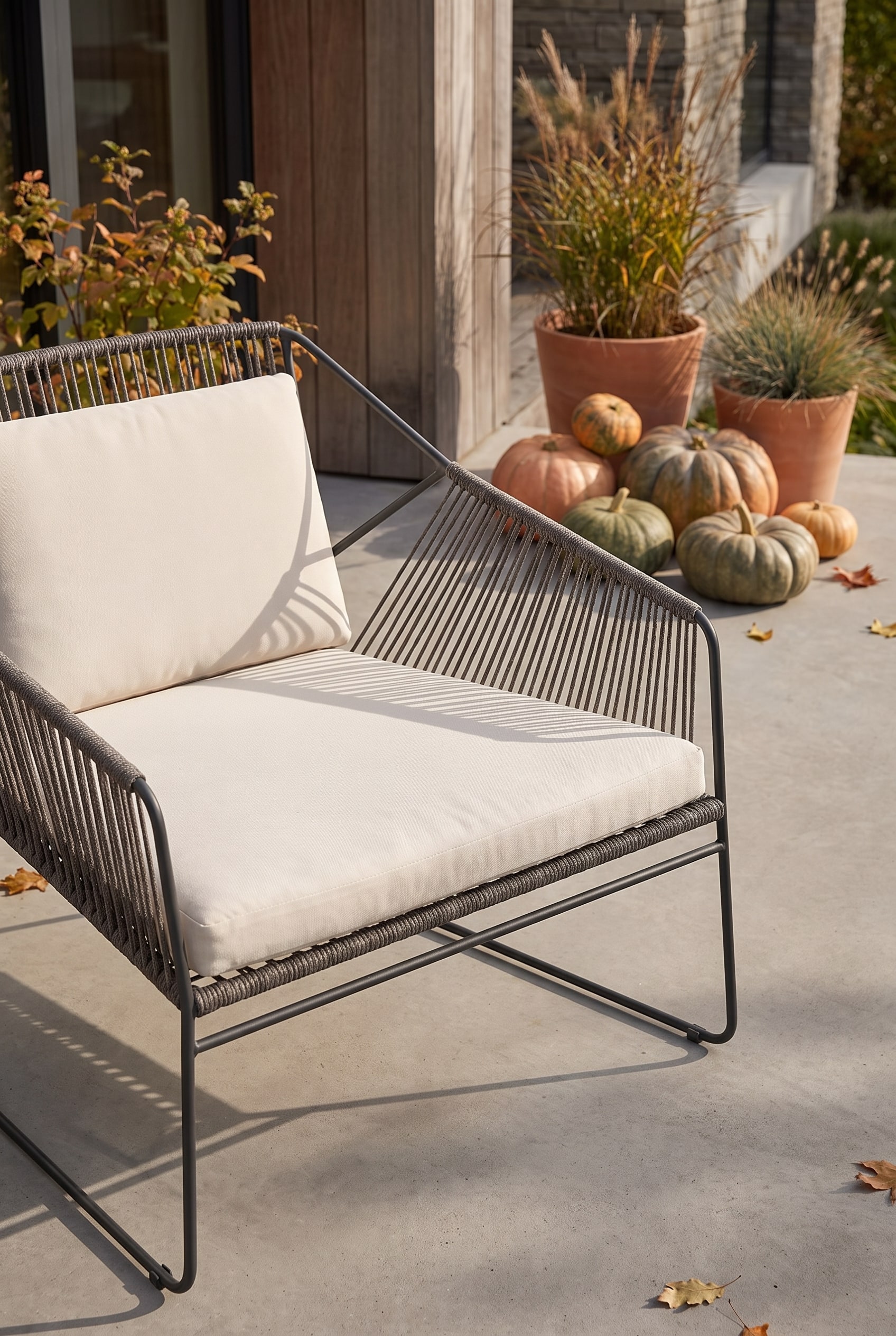 Chaise de jardin avec tressage de corde a&eacute;r&eacute; et cadre en acier inoxydable sur un sol en b&eacute;ton &agrave; c&ocirc;t&eacute; de plantes