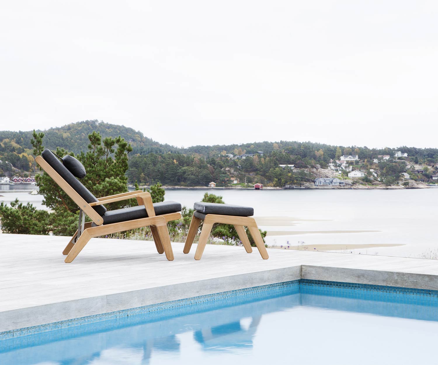 Oasiq Skagen Design Liegestuhl aus Teak mit Skagen Hocker am Swimmingpool