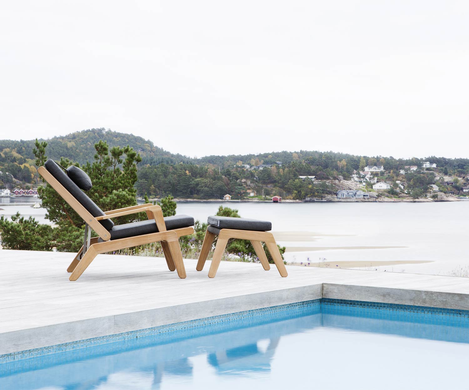 Oasiq Skagen Design Liegestuhl aus Teak mit Skagen Hocker am Swimmingpool Oasiq Skagen Design Liegestuhl aus Teak mit Skagen Hocker am Swimmingpool