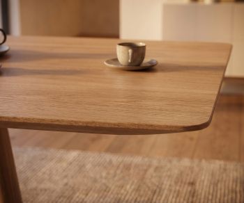 mos-i-ko 001 a dining table in light oak, close-up of the rounded tabletop corner in a warm, modern dining room.