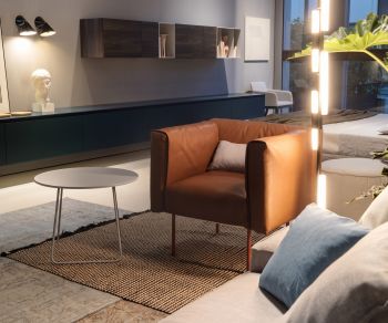 Orbis side table by Novamobili as a round coffee table in a modern living room next to a brown leather armchair.