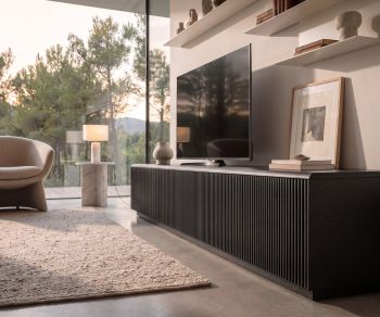 Punt Malmö TV lowboard with dark oak slatted front in a modern living room with floor-to-ceiling windows.
