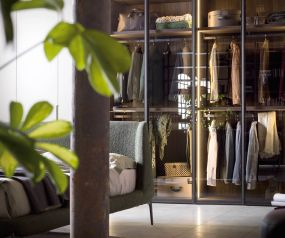 Glass door designer wardrobe Perry from Novamobili behind bed