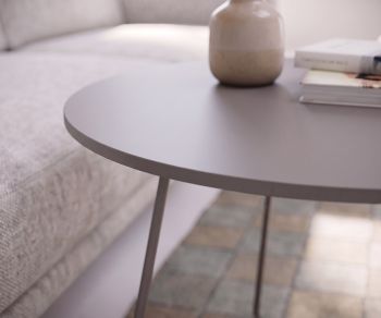 Novamobili Orbis coffee table used as a side table in the living room next to a sofa, round matte grey top with a vase.