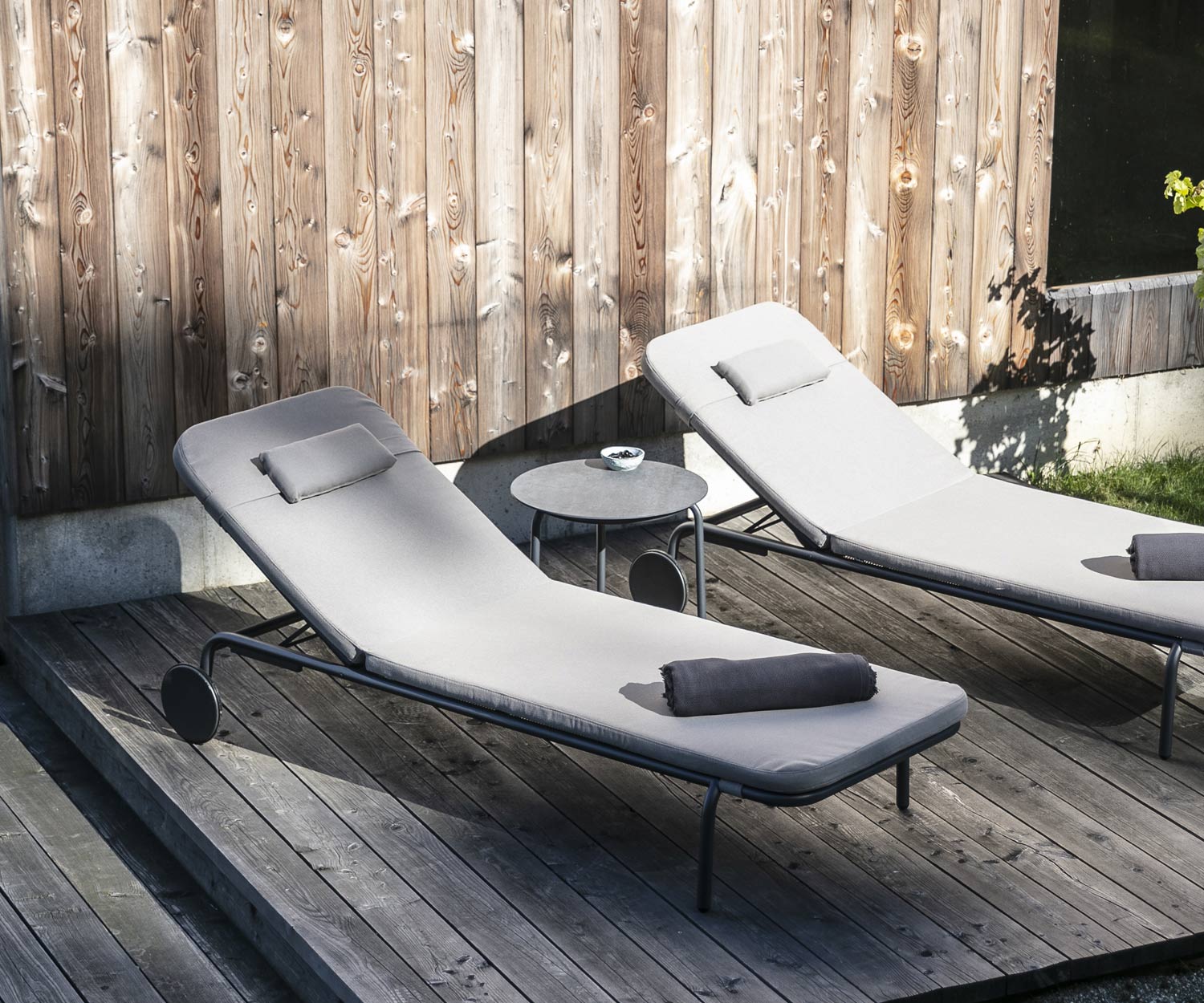 Starling design side table from Todus with two garden loungers on a wooden veranda